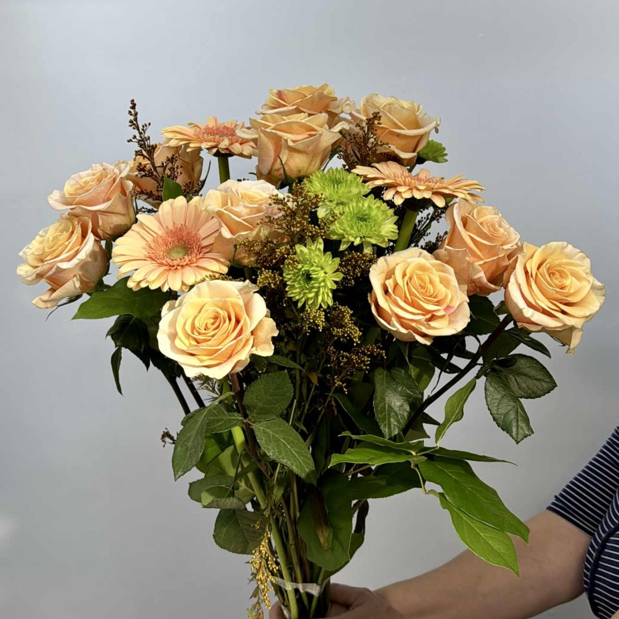 Bouquet of peach roses and gerbera daisies with green accents