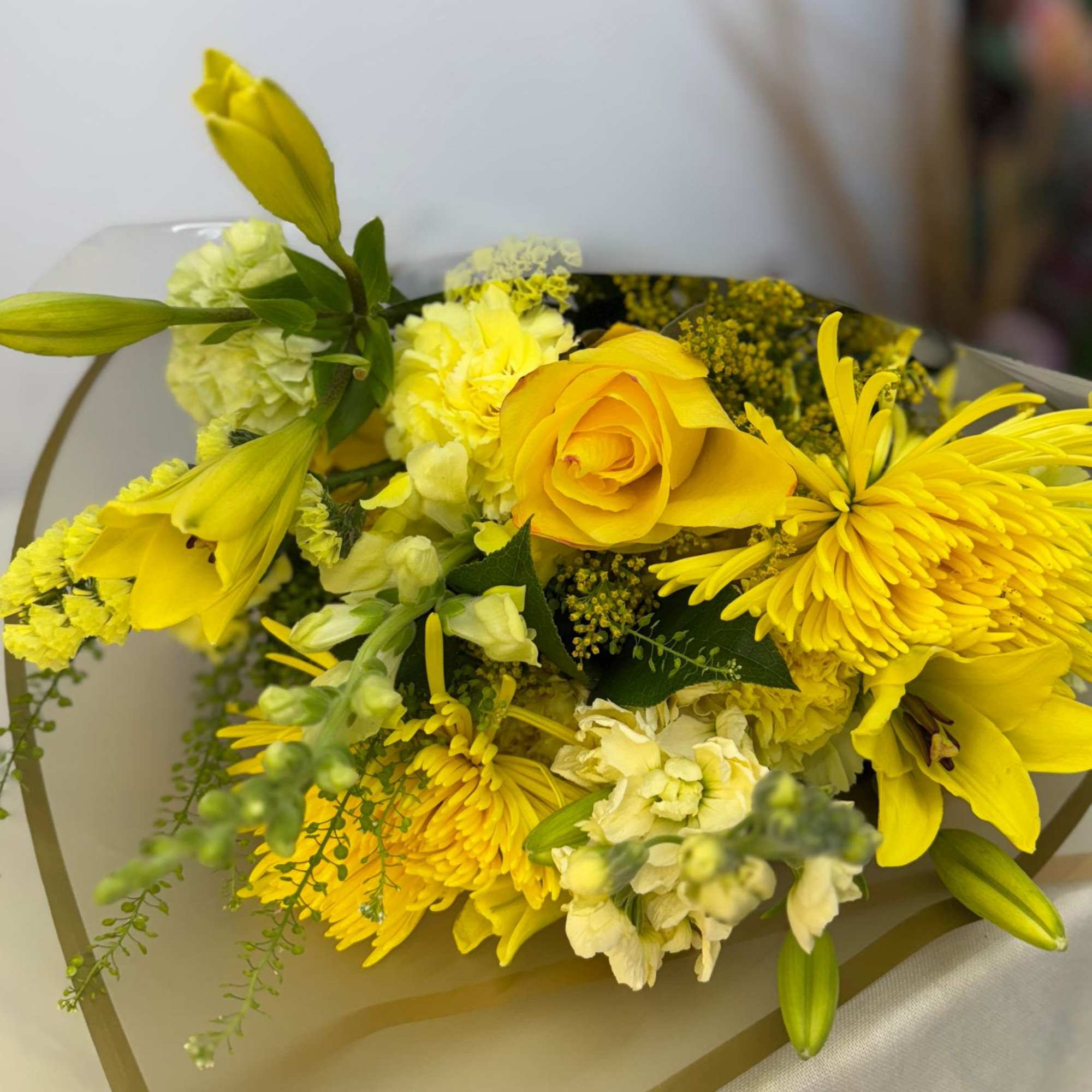 Yellow bouquet with roses, lilies, and chrysanthemums wrapped in paper