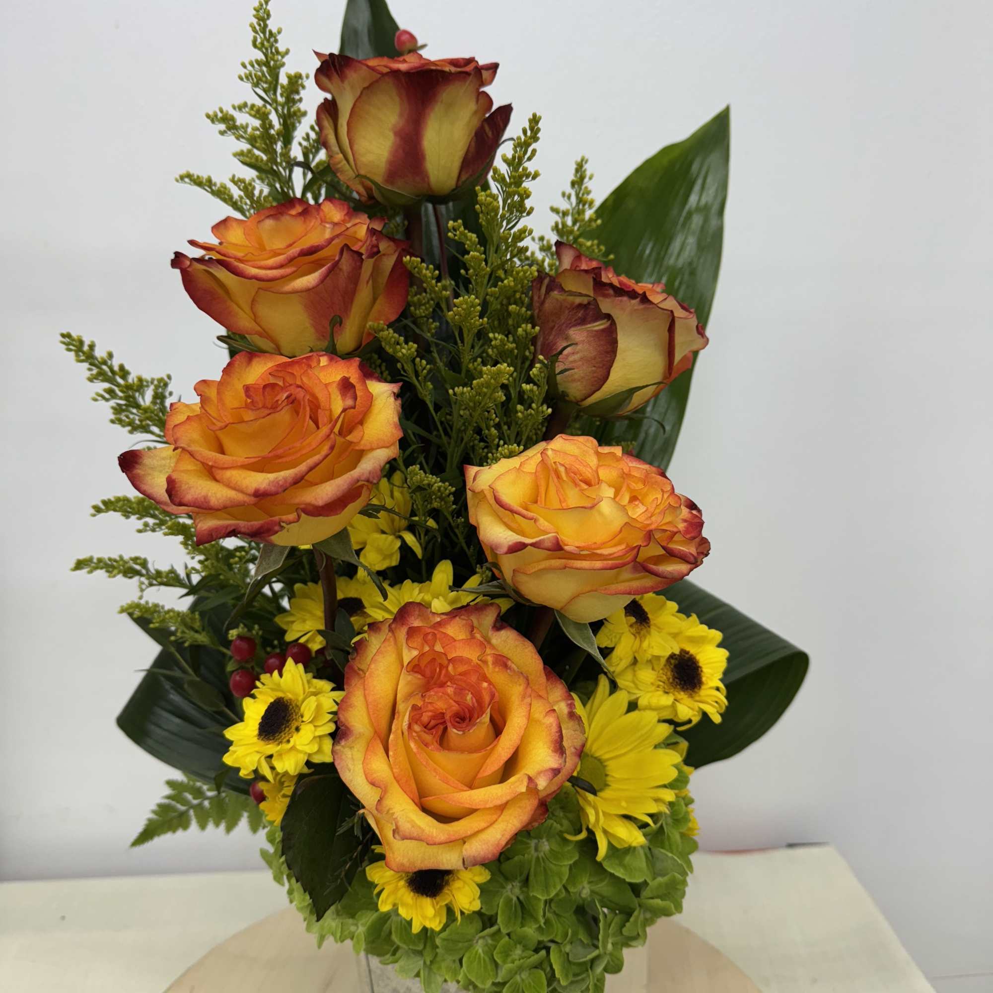 Orange roses and yellow daisies in a metal vase