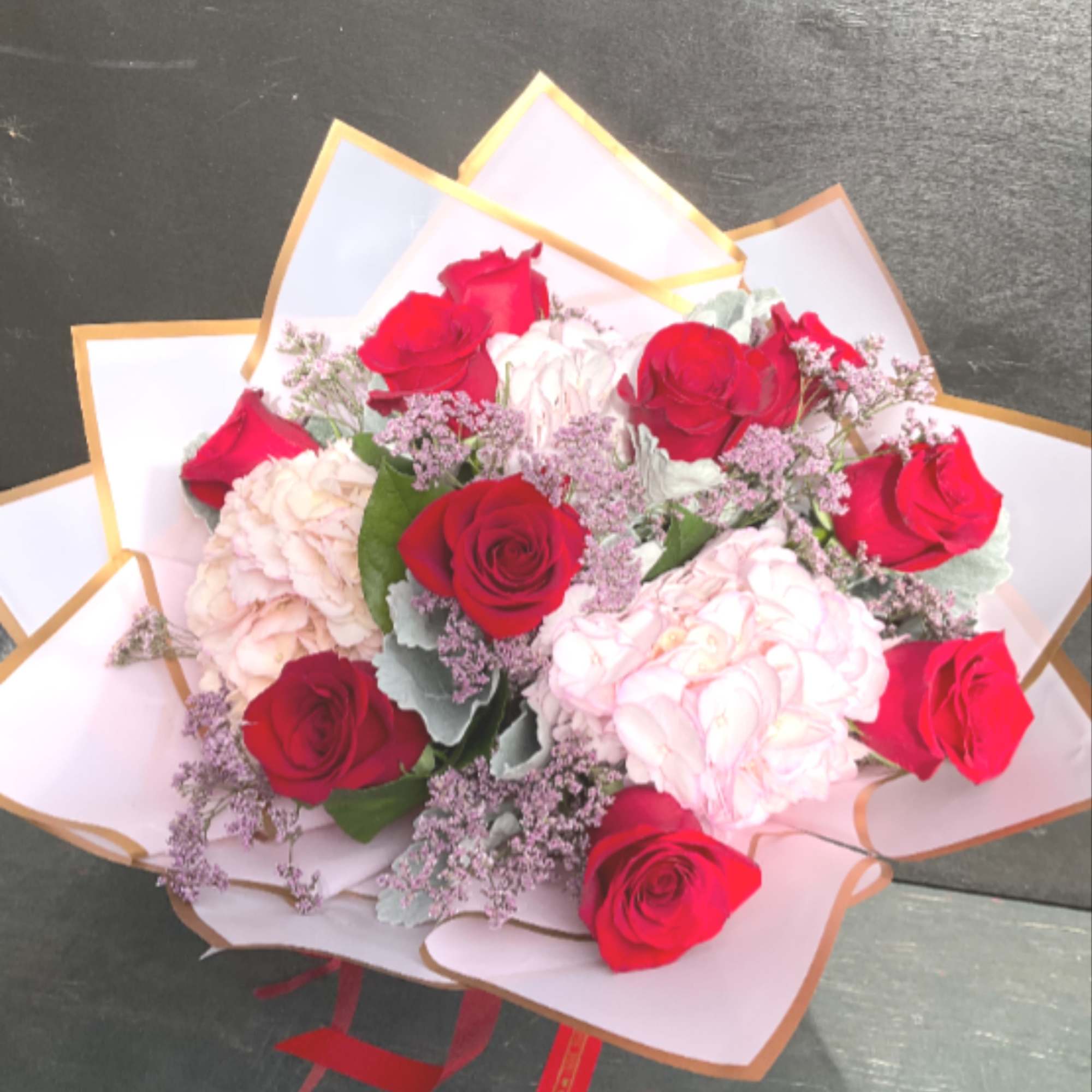 Bouquet of red and pale pink roses wrapped in white paper