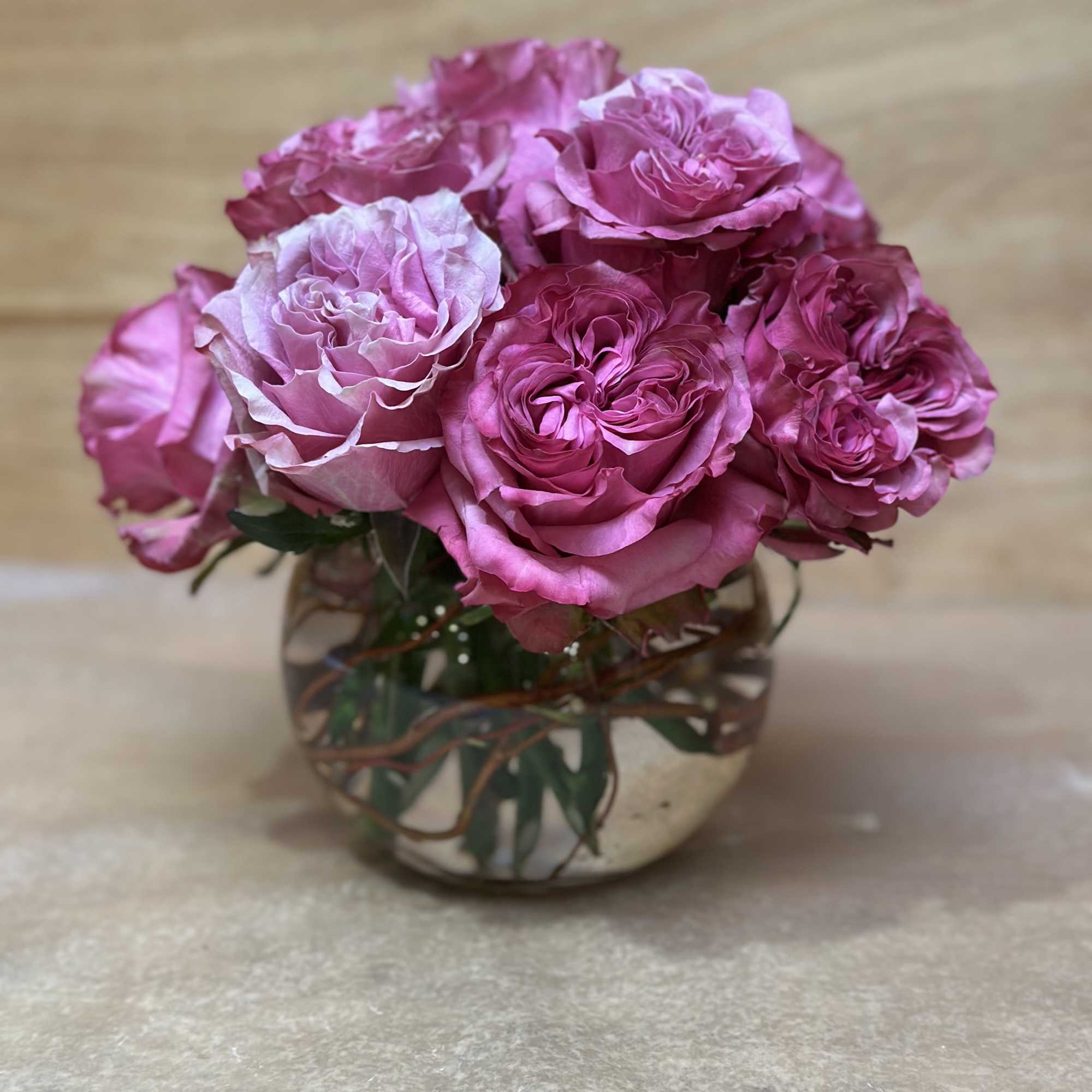 Pink roses arranged in a round glass vase
