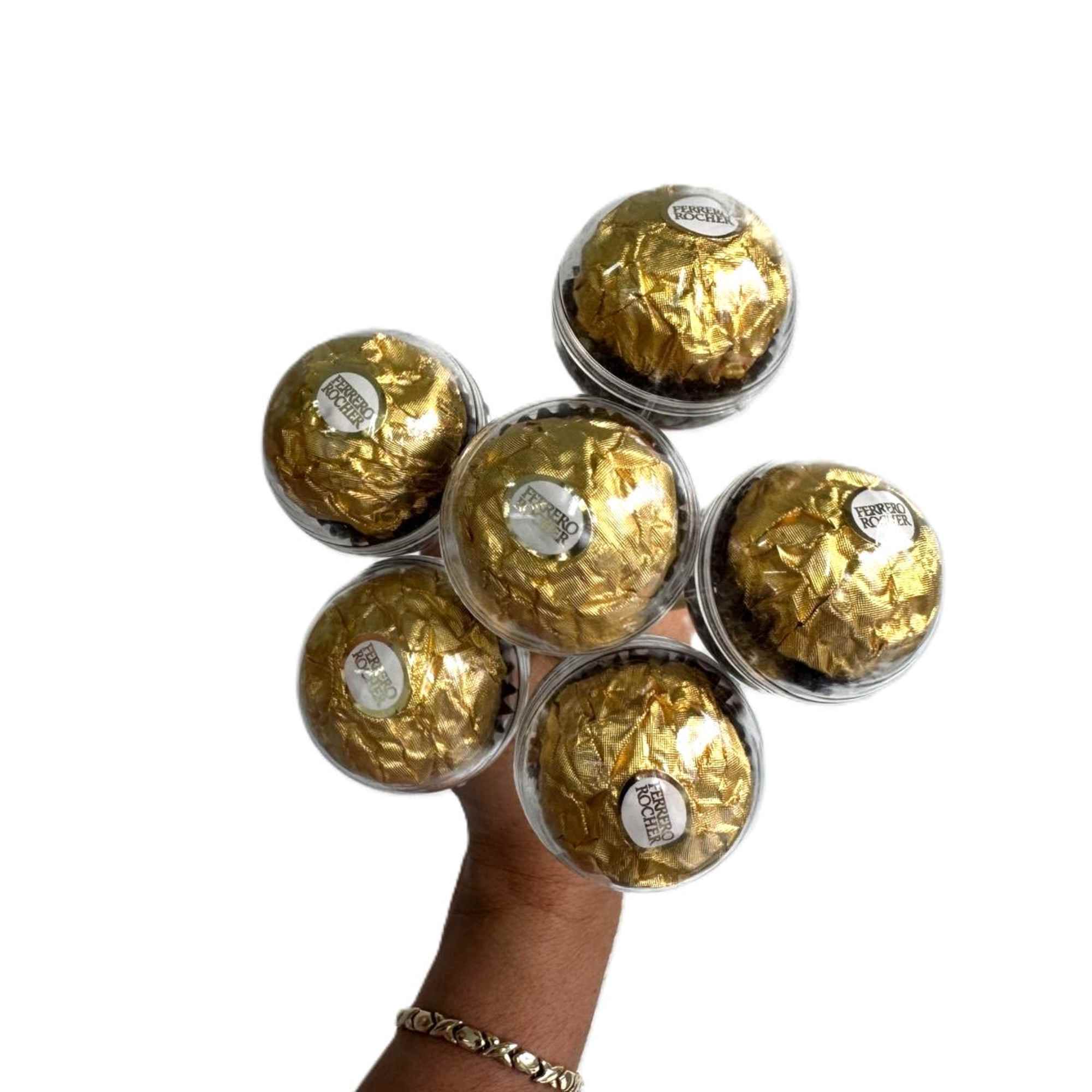 Hand holding six Ferrero Rocher chocolates in clear plastic cups