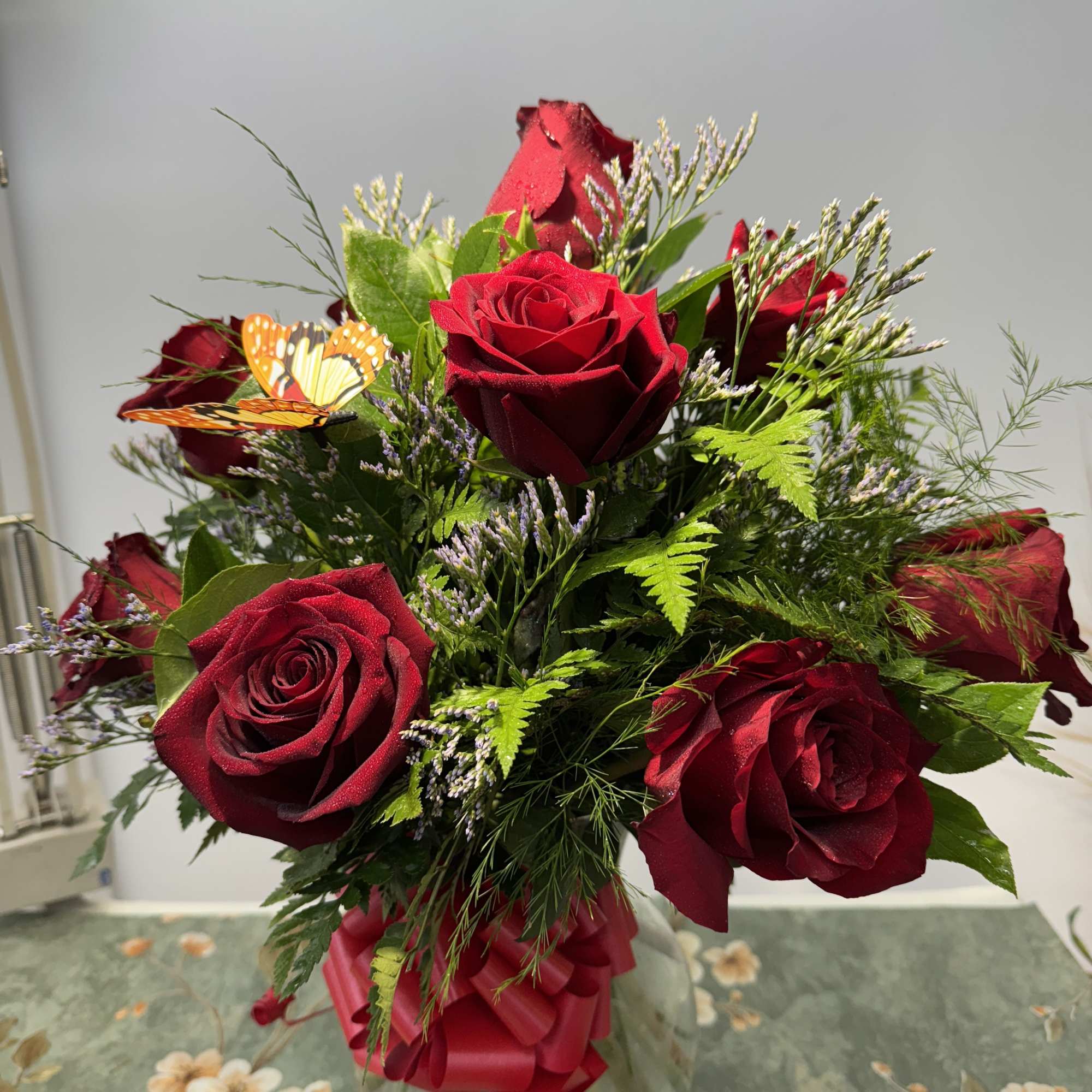 Bouquet of red roses in a clear glass vase with a butterfly decoration