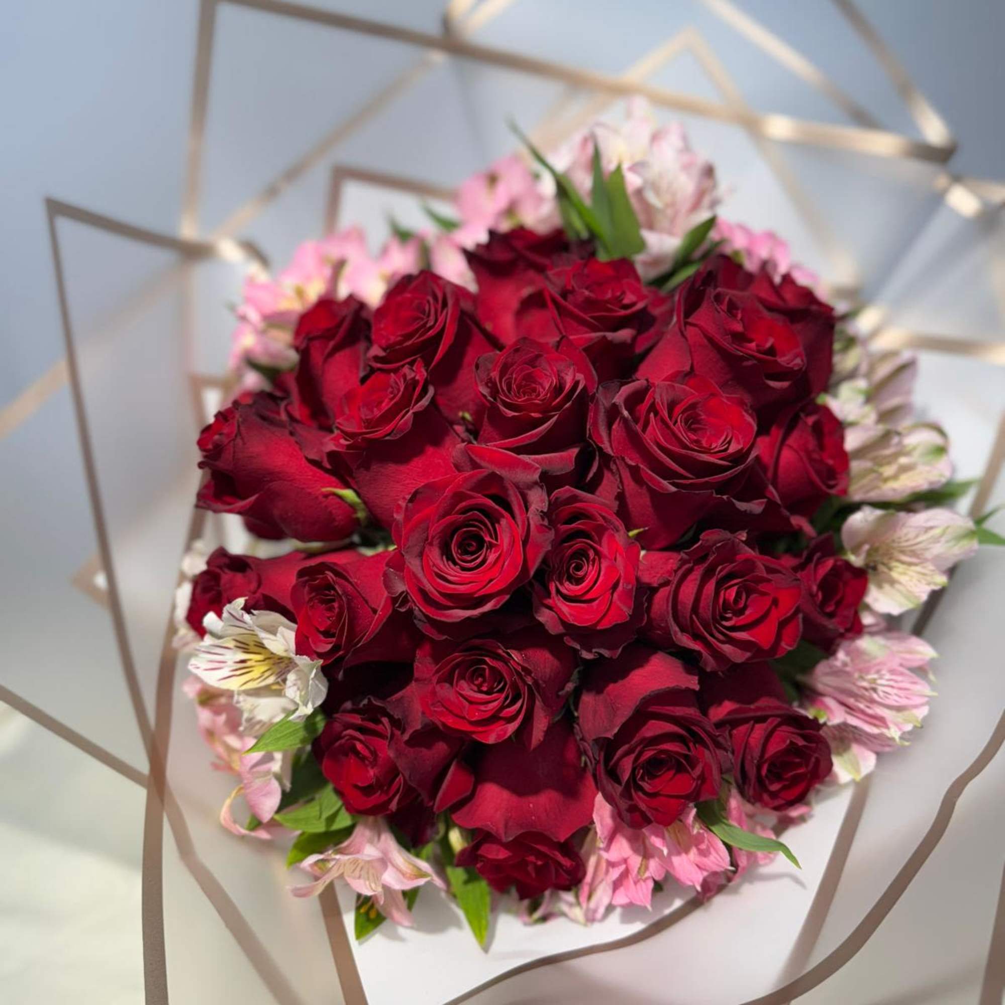 Bouquet of red roses with pink flowers wrapped in clear paper