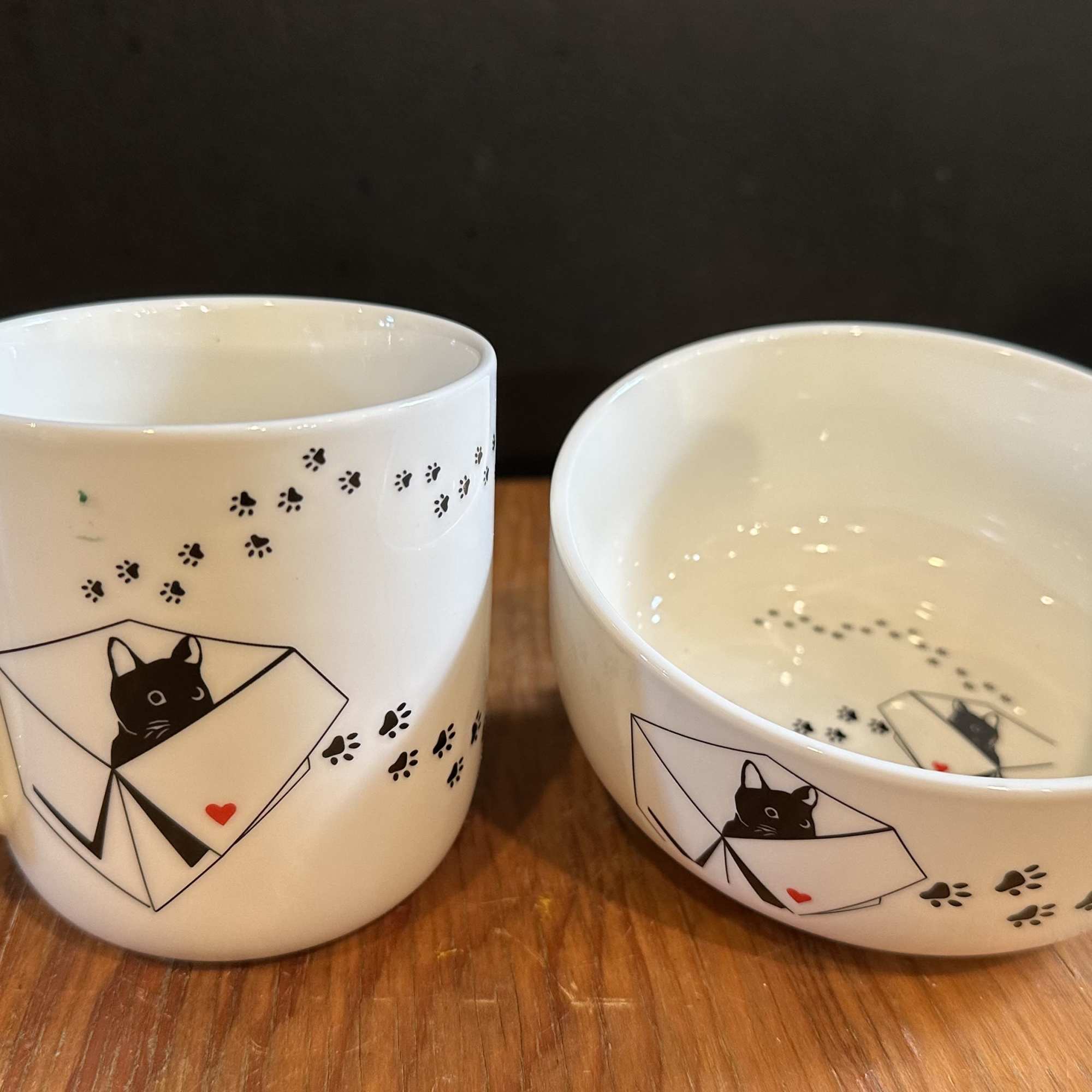 White mug and bowl with a black cat and paw print design