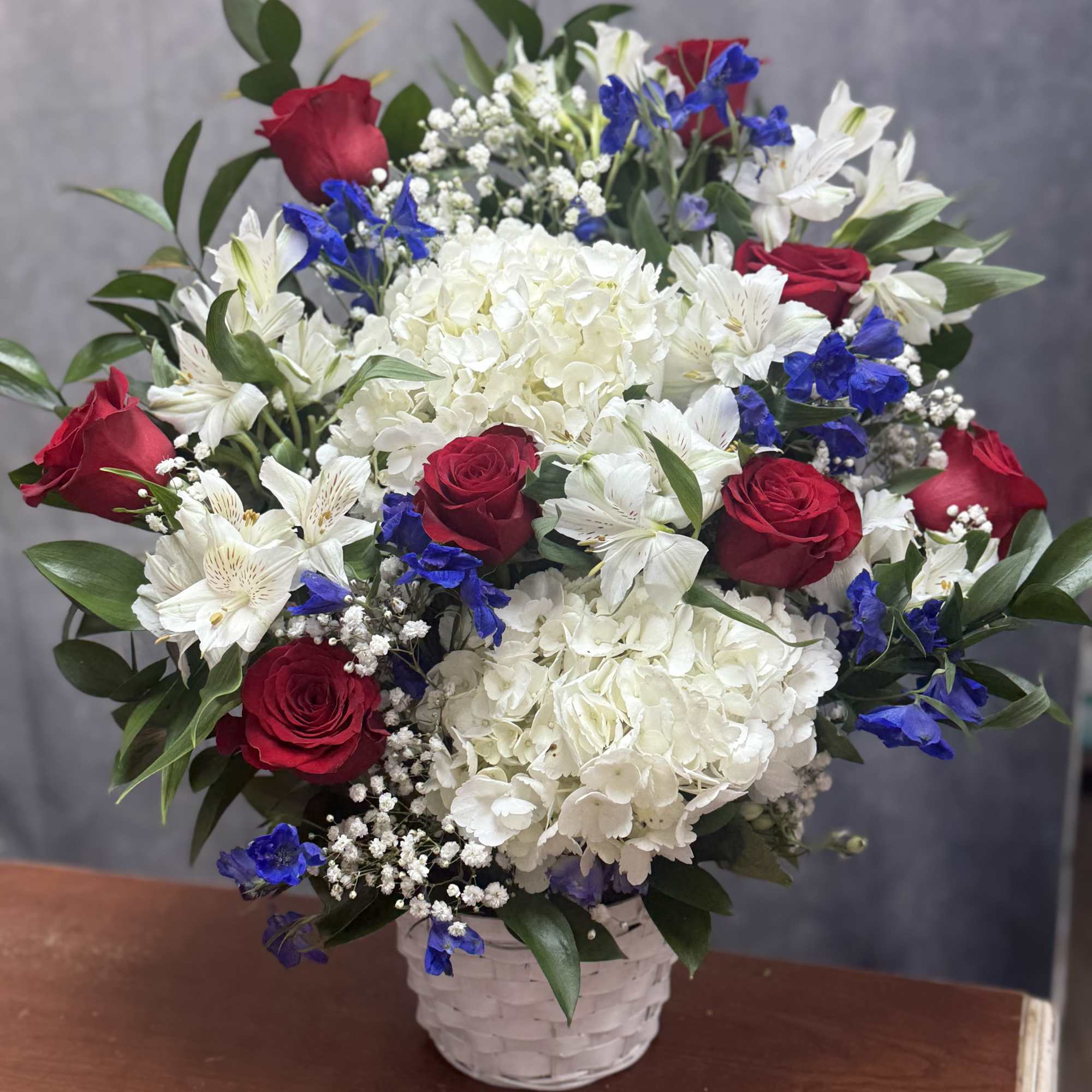 Red roses, white hydrangeas and lilies with blue accents in a white