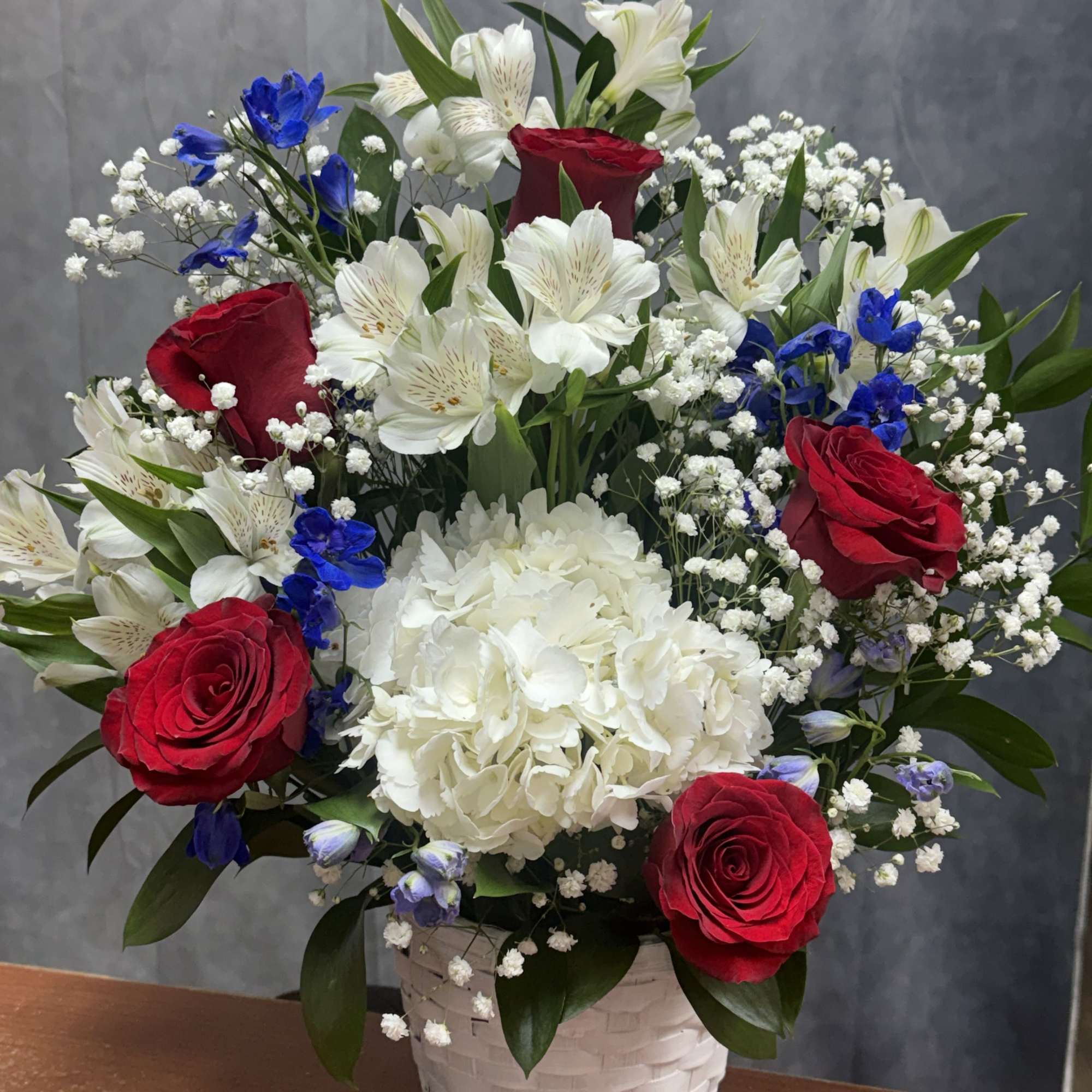 Red roses, white hydrangeas and lilies with blue accents in a white