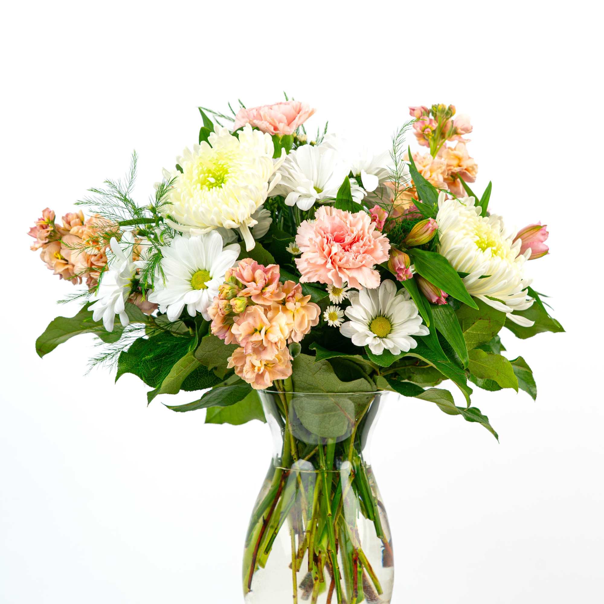 Mixed bouquet of white daisies, pale peach carnations, and mums in a clear glass vase