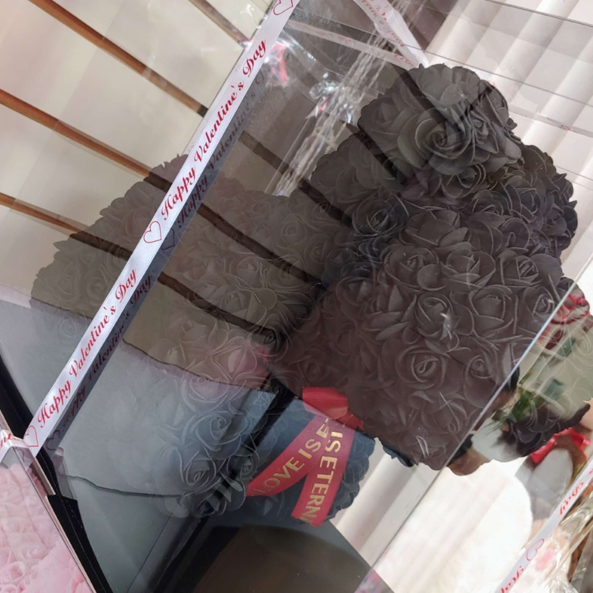 Black rose-shaped gift box with a red ribbon and teddy bear