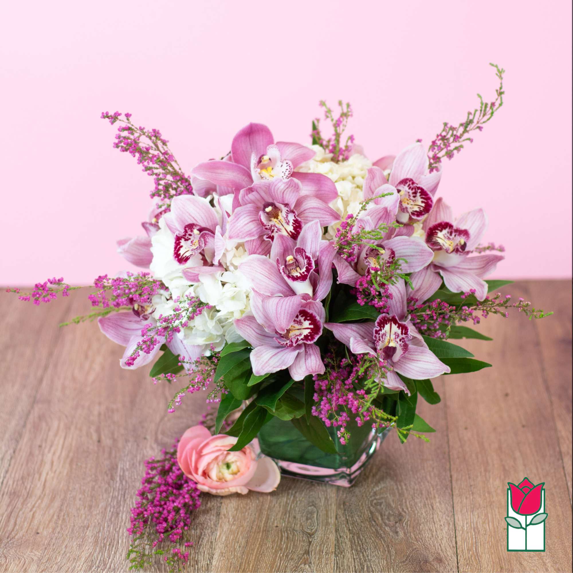 Pink orchids and white hydrangeas in a glass vase with a pink flower on the table