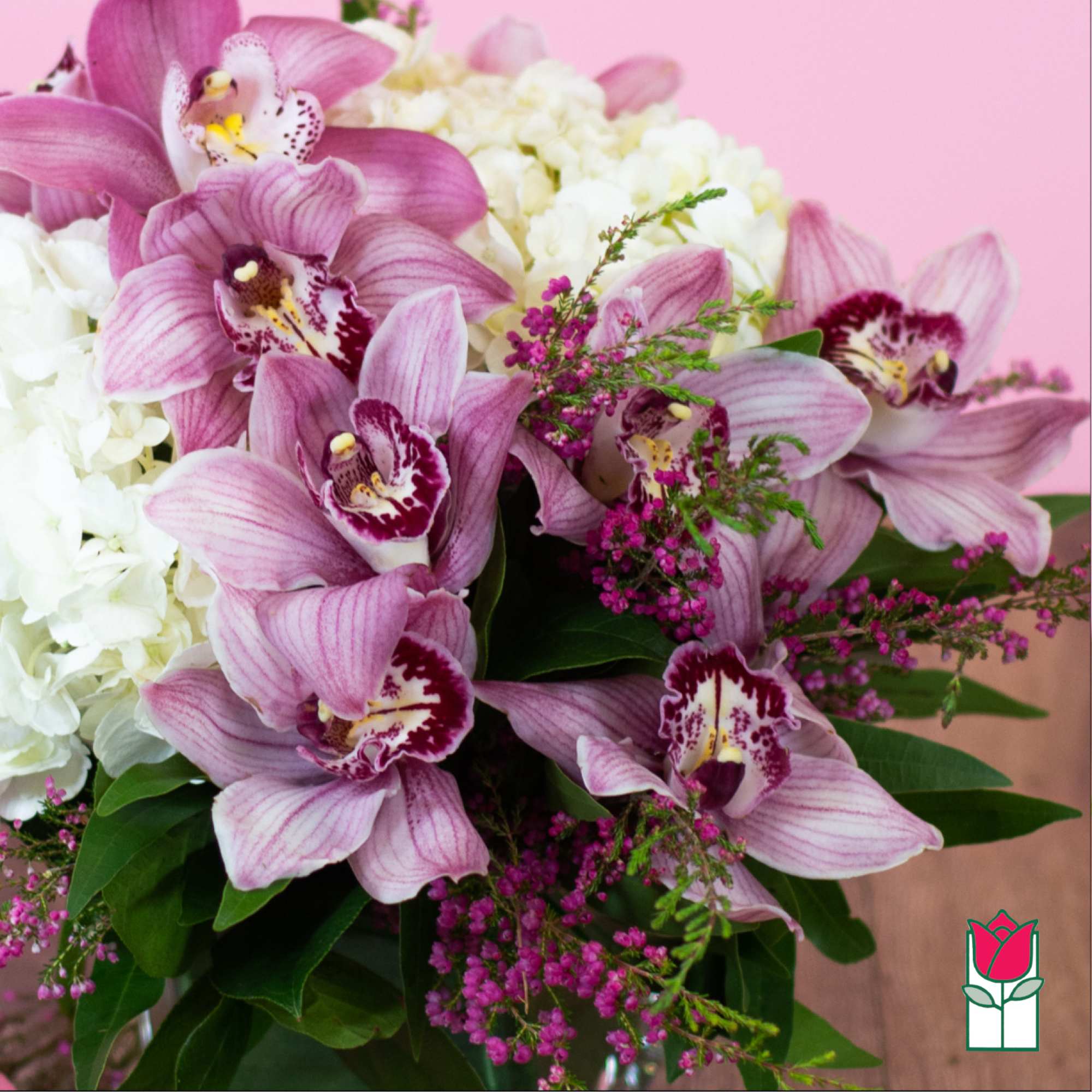 Pink orchids arranged with white hydrangeas and small purple filler flowers