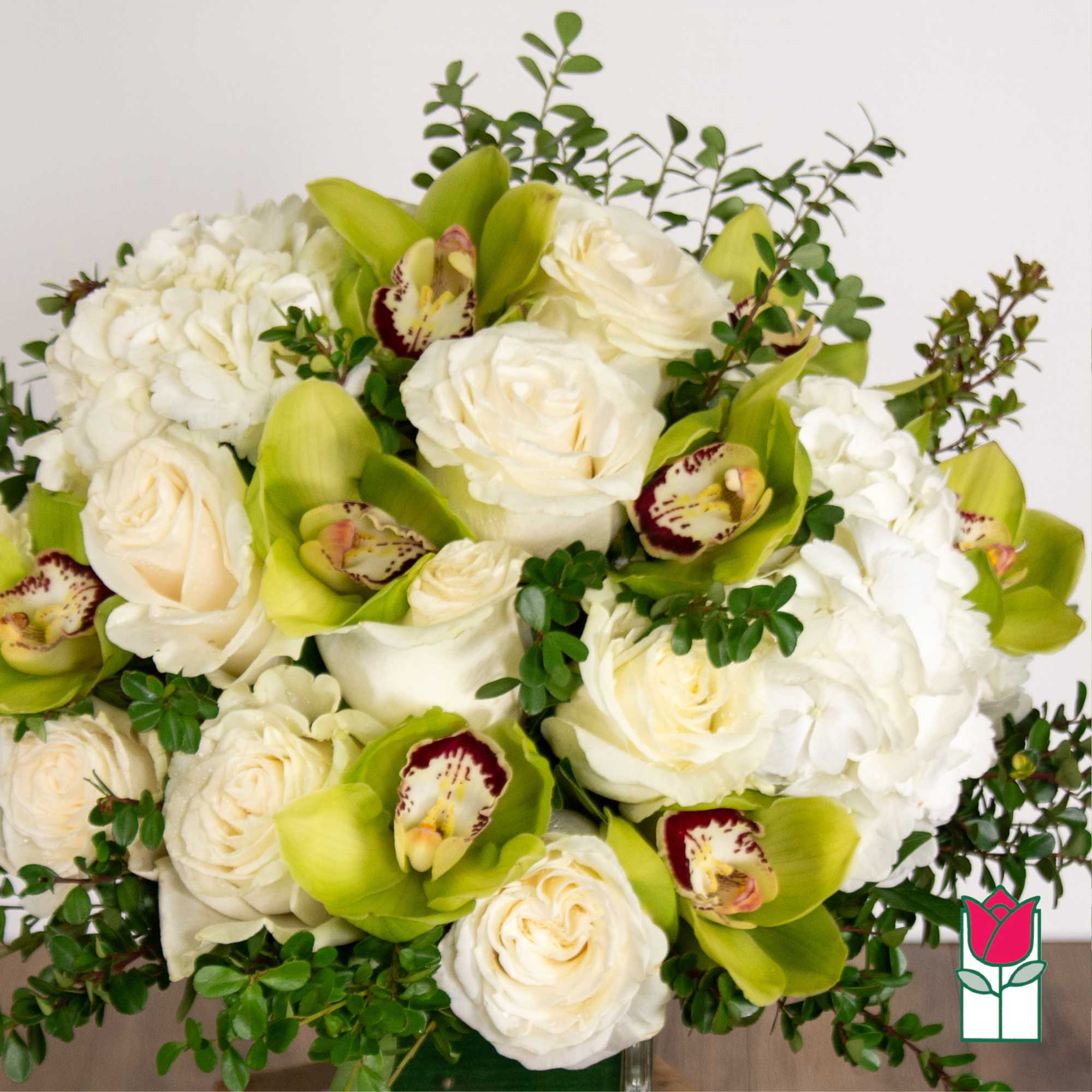 White roses and green orchids arranged with white hydrangeas.