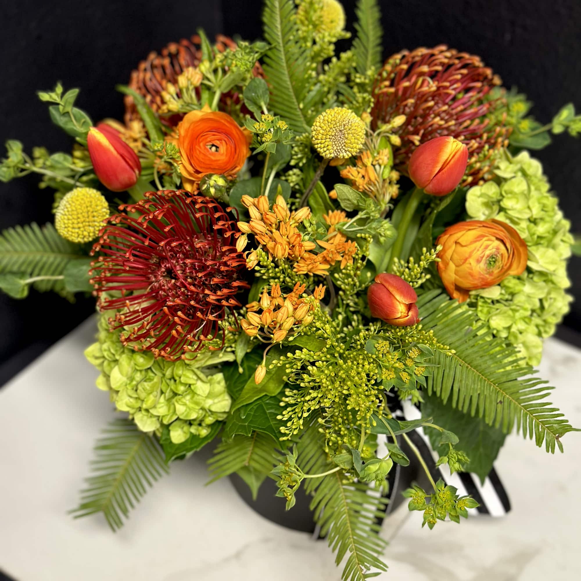 A vibrant arrangement of our unique Pincushion Proteas accented with sunset colored
