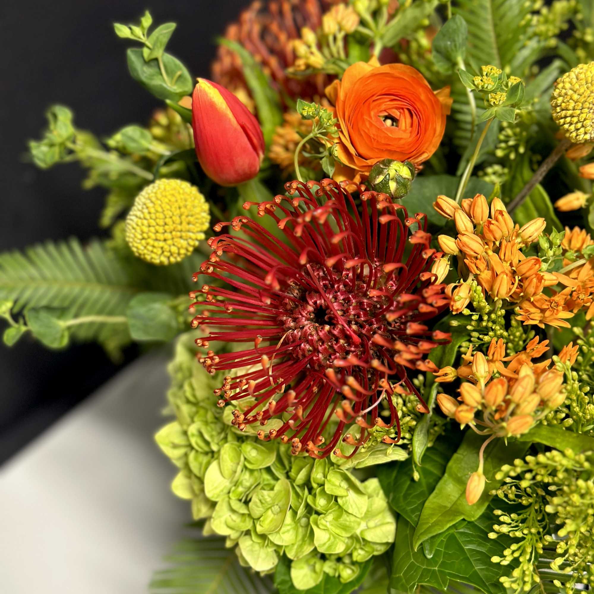 A vibrant arrangement of our unique Pincushion Proteas accented with sunset colored