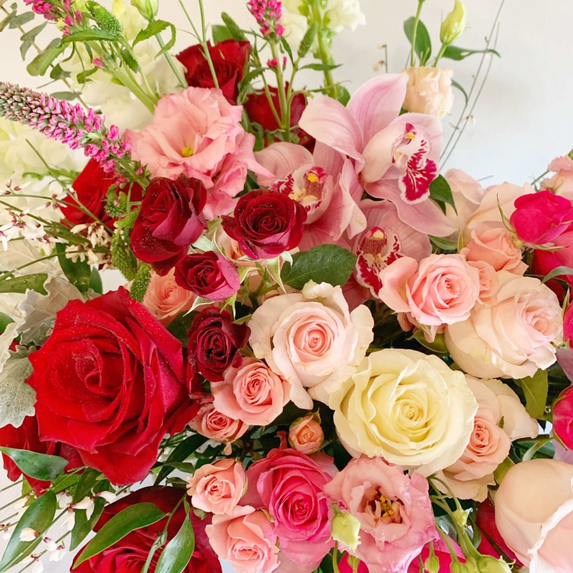 Mixed bouquet of red, pink, and cream roses with pink orchids