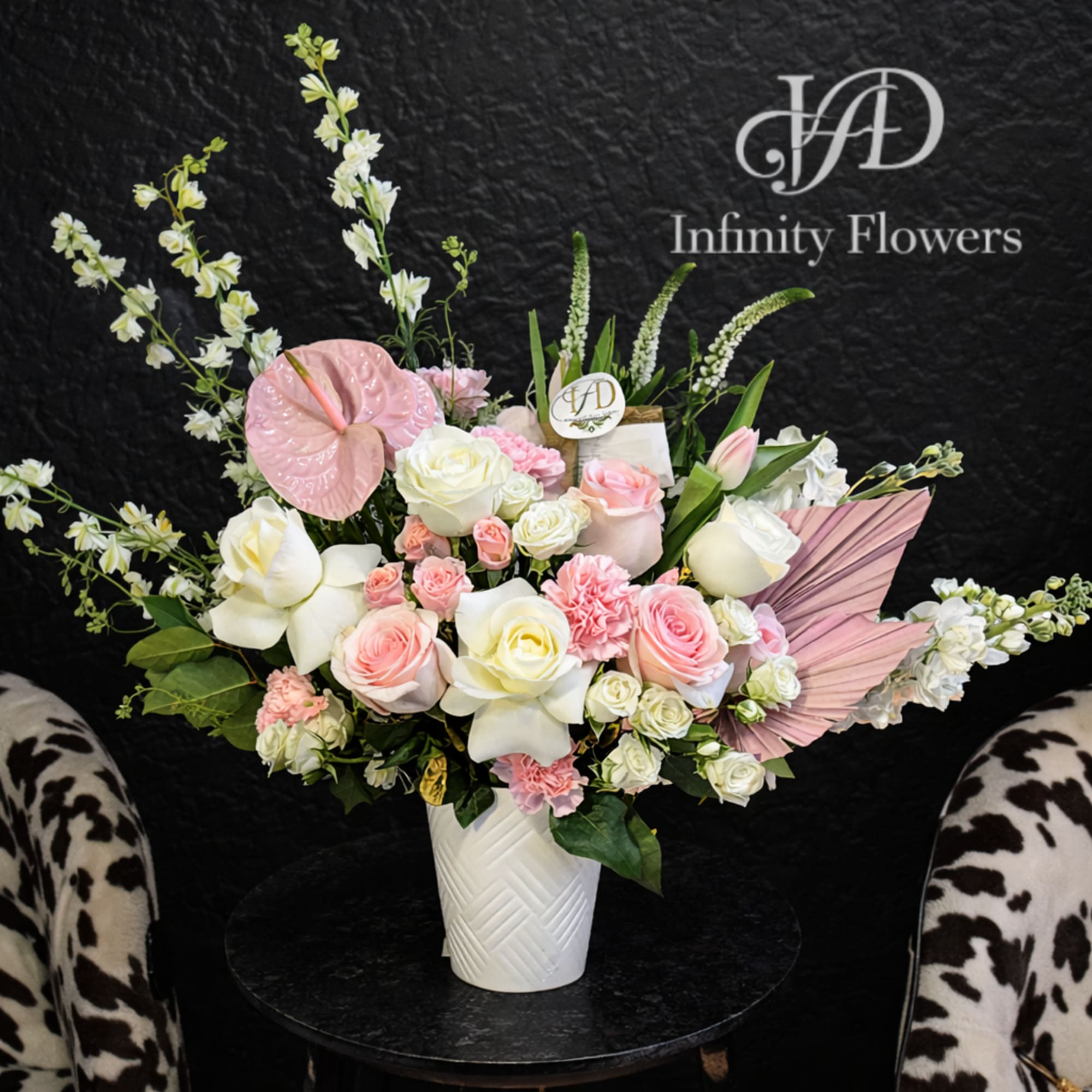 Pink and white floral arrangement in a white vase with decorative leaves.