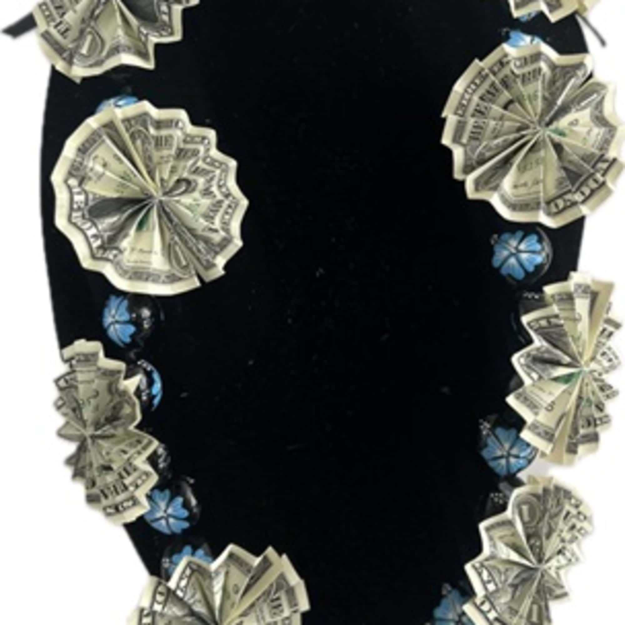 Black velvet necklace display with dollar-bill rosettes and blue bead accents