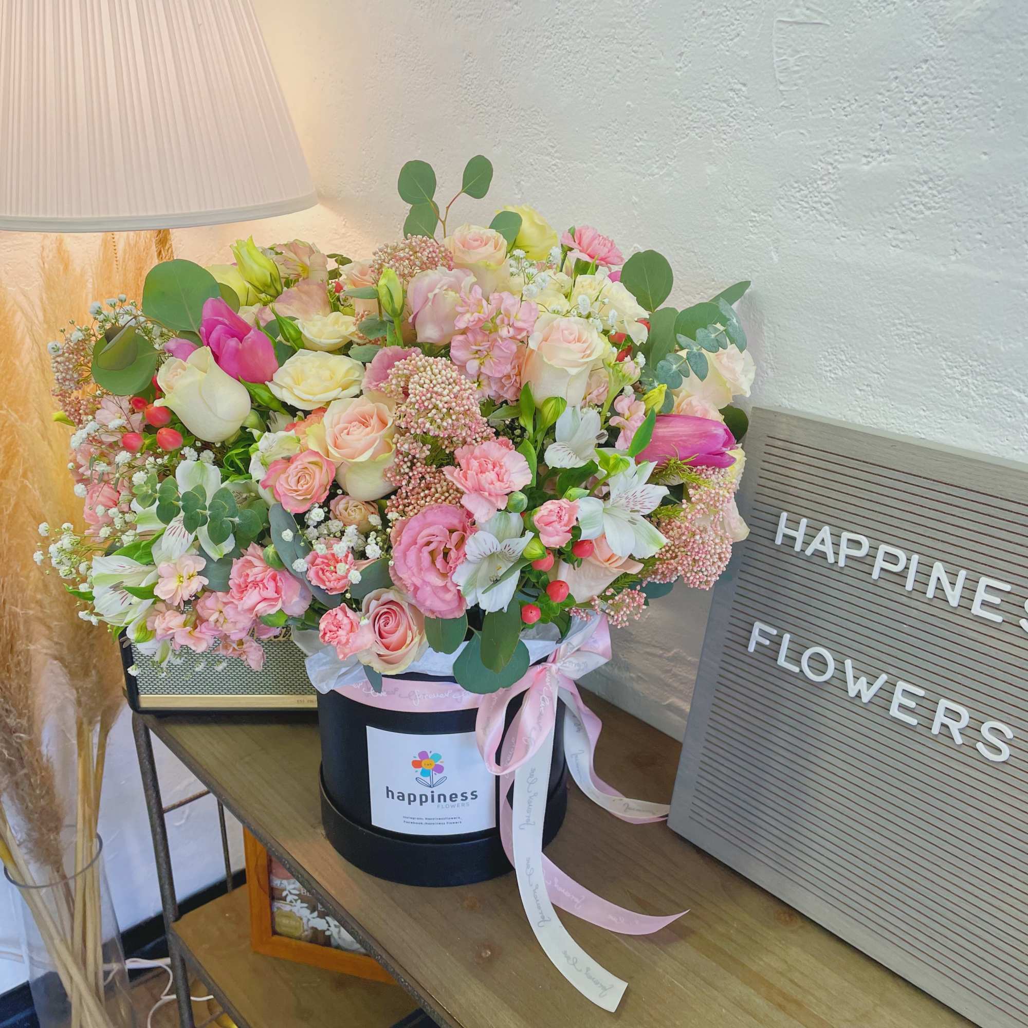 Mixed pink and white flower arrangement in a black hatbox