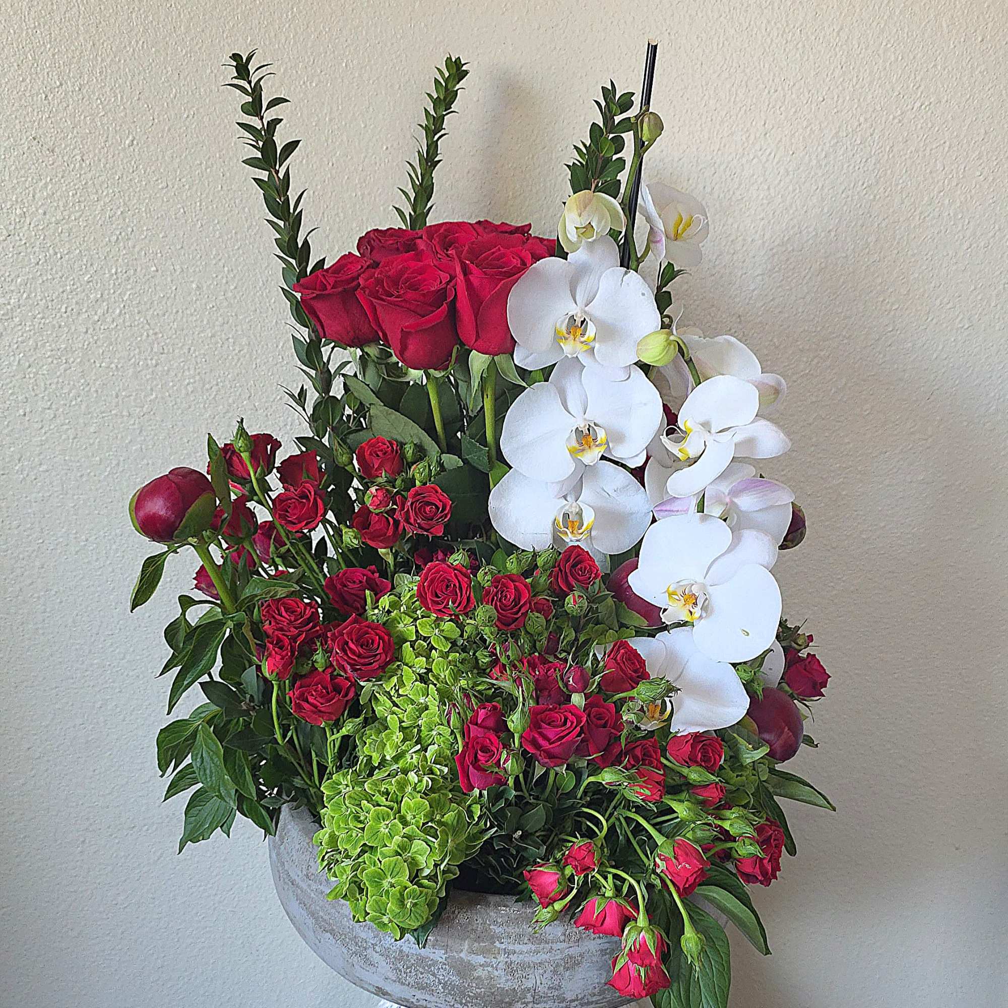 Deep clusters of deep red roses meet cascading white Phalaenopsis orchids in