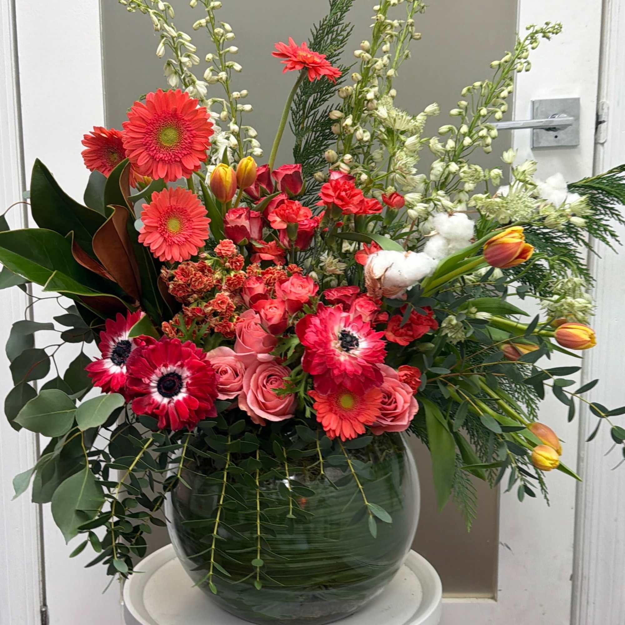 Large mixed flower arrangement in a glass vase with pink and red blooms