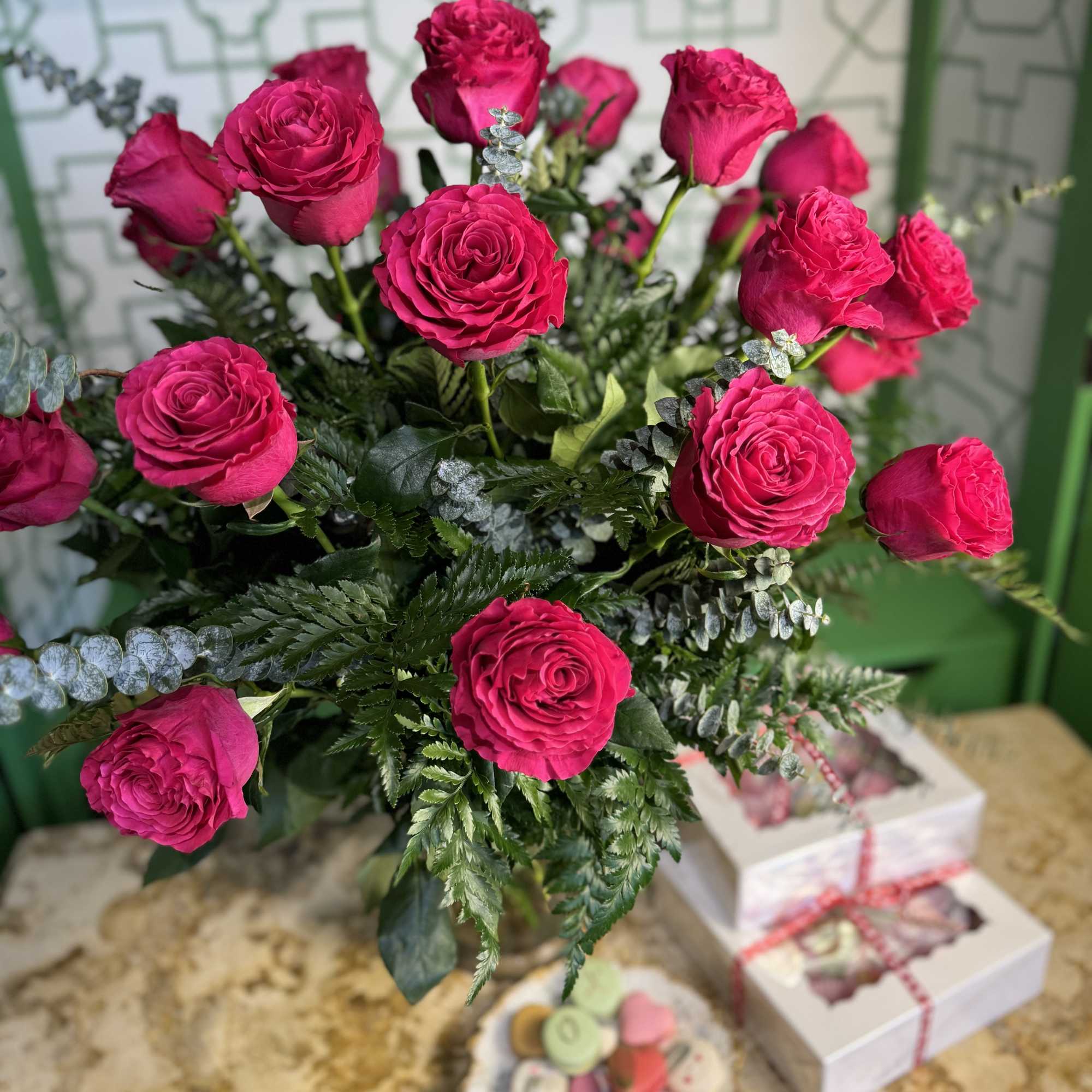 Bouquet of bright pink roses with mixed greenery in a vase