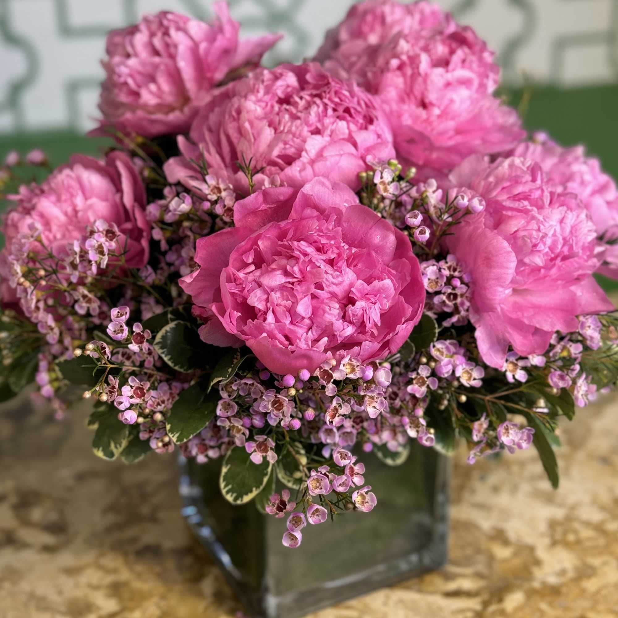 Pink peonies arranged in a square glass vase