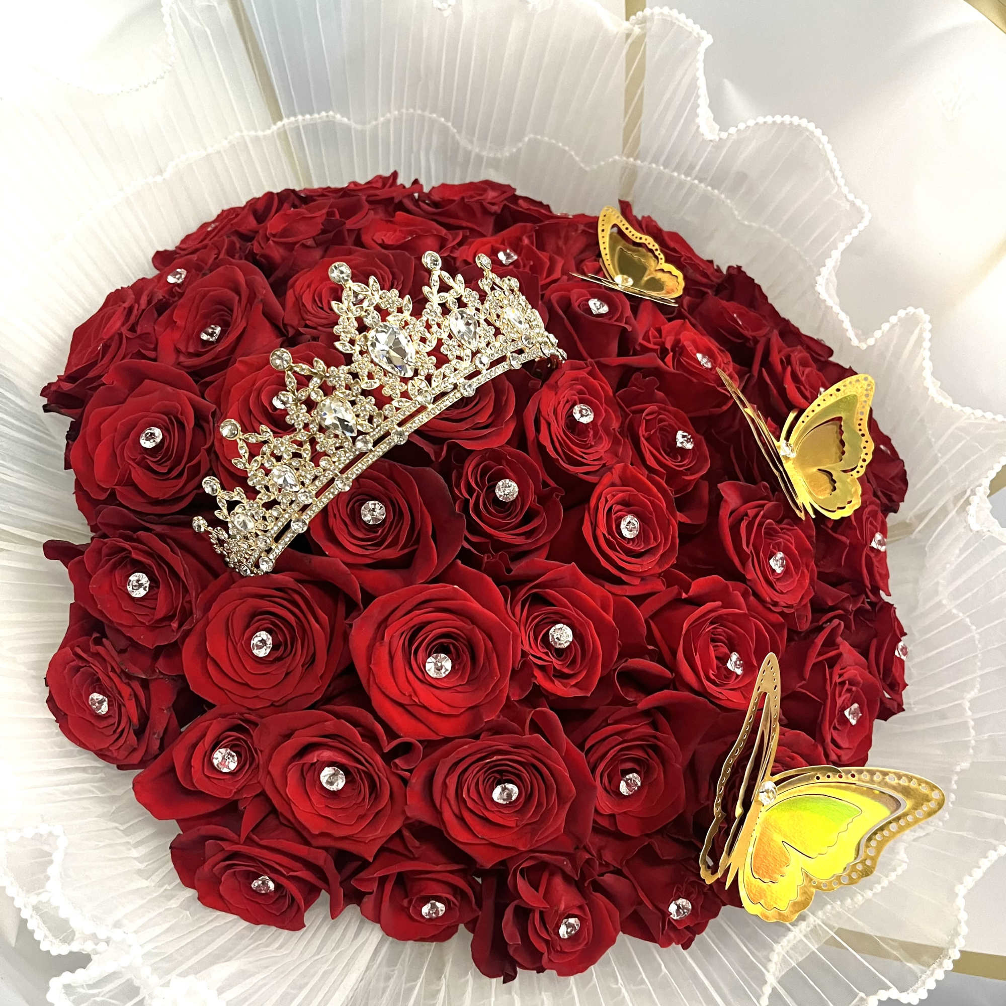 Red rose bouquet with a jeweled tiara and yellow butterfly decorations
