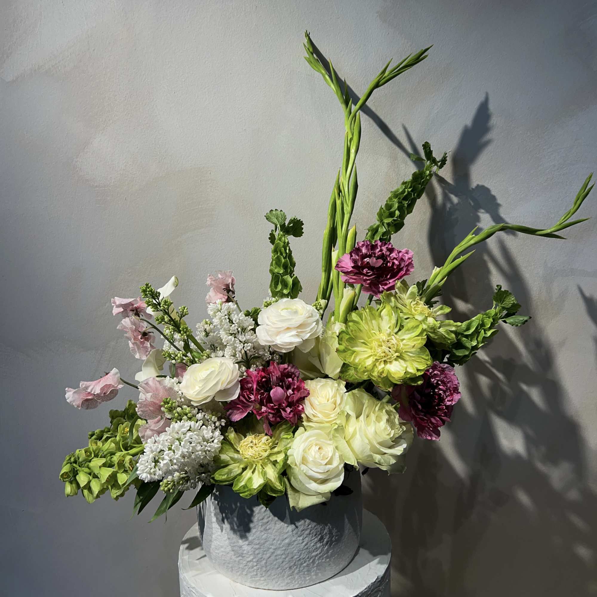 Mixed bouquet in a gray vase with white, pink, and green blooms