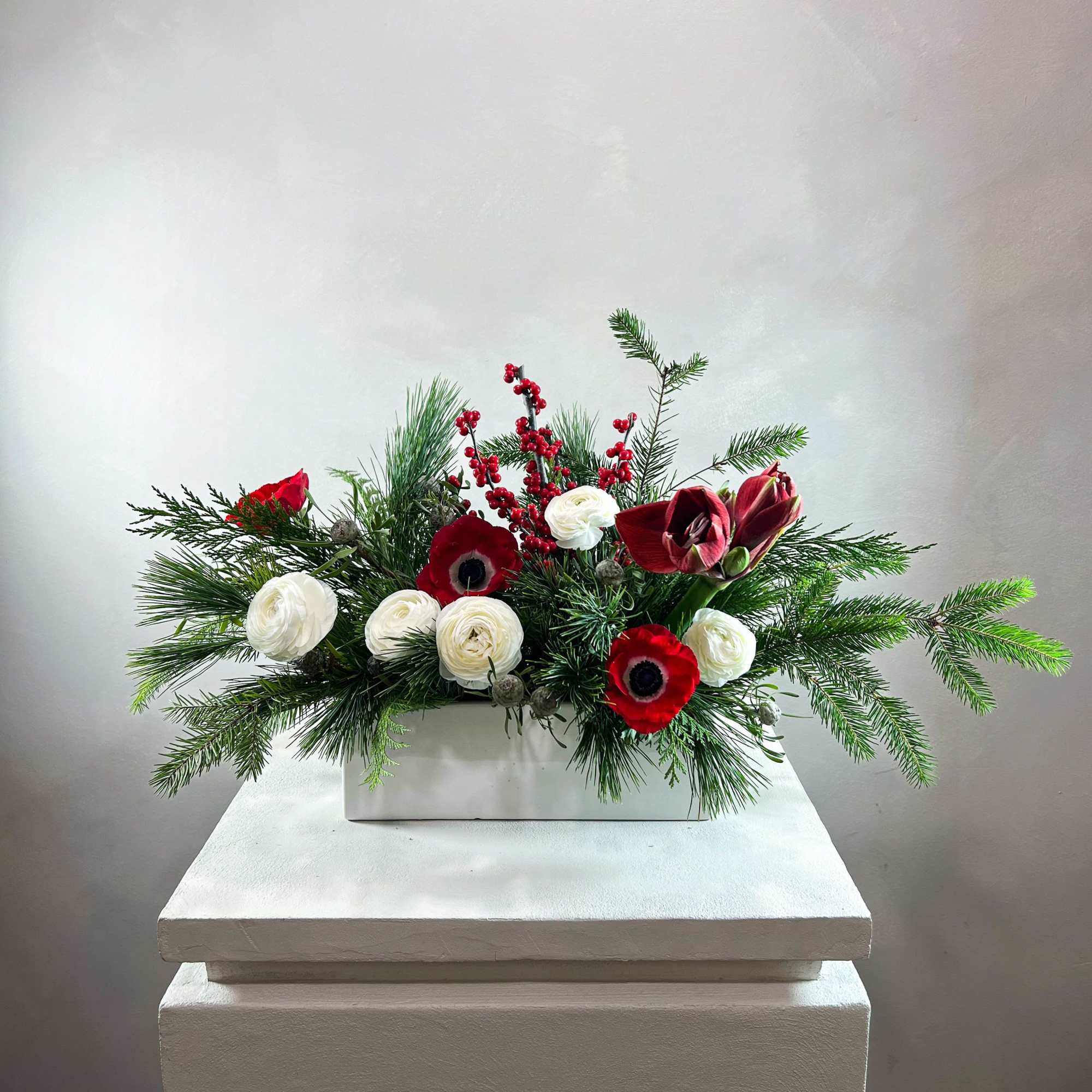 Holiday floral arrangement with red and white blooms in a white box