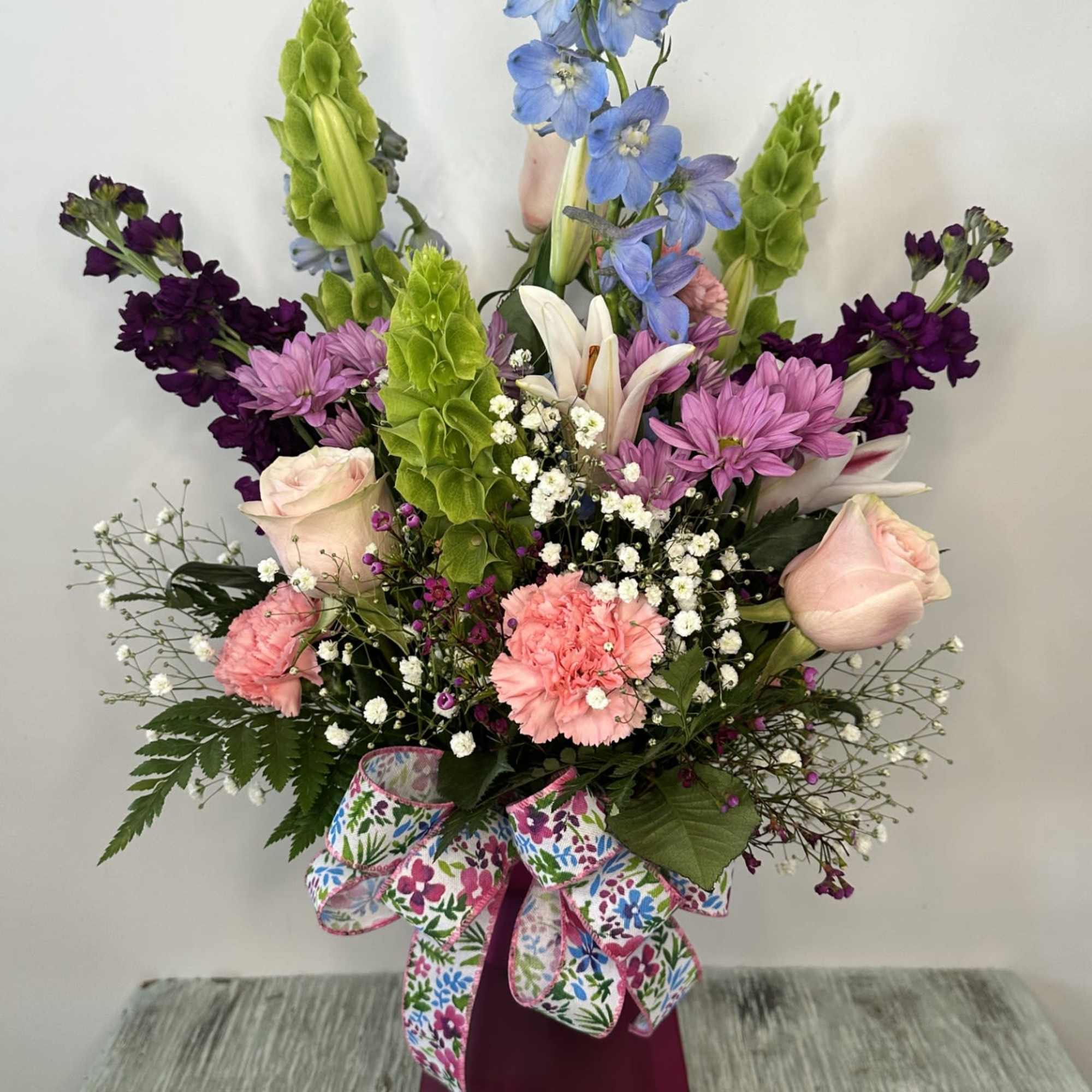 Mixed bouquet in a burgundy vase with pink, purple, blue, and white flowers