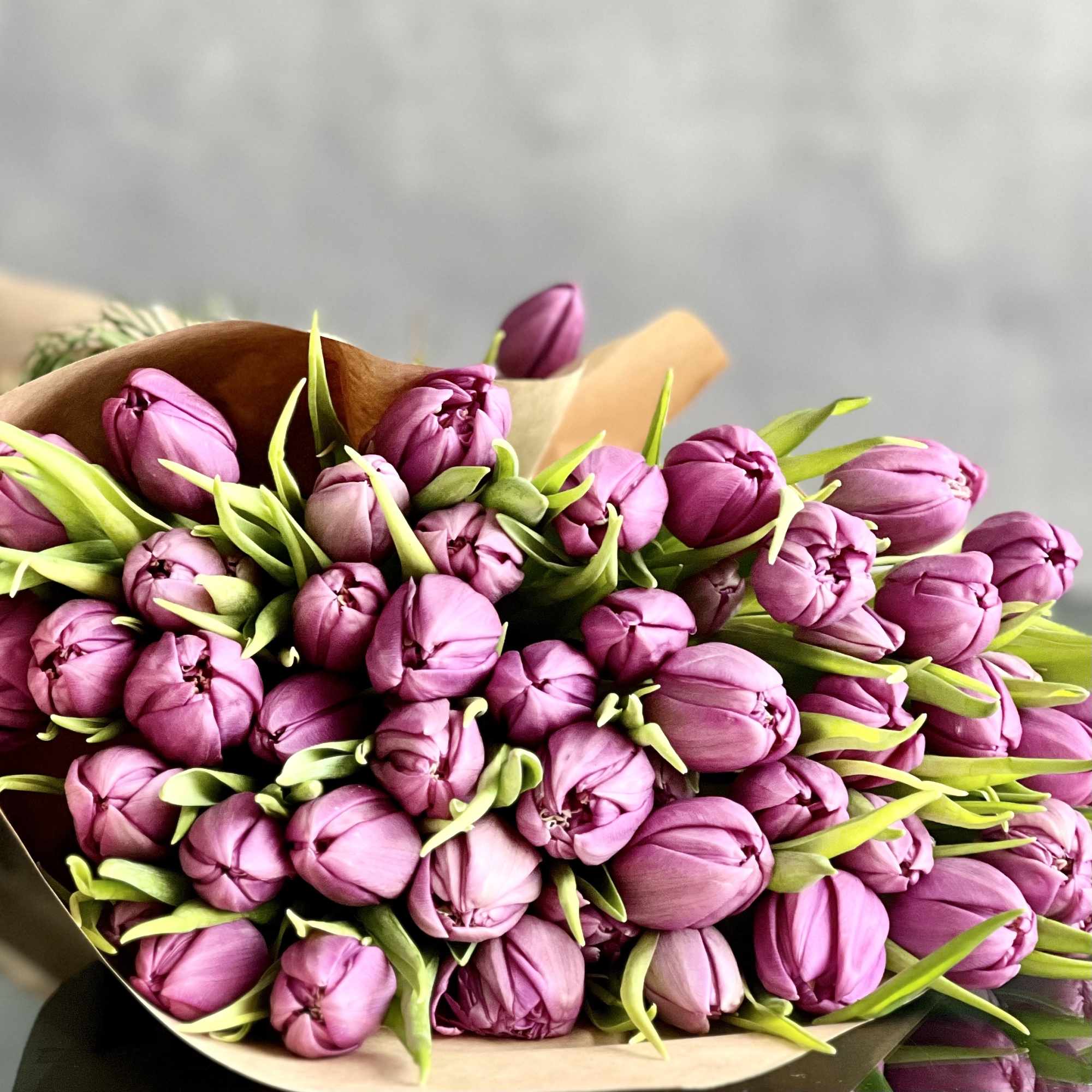 Bouquet of pink-purple tulips wrapped in brown paper