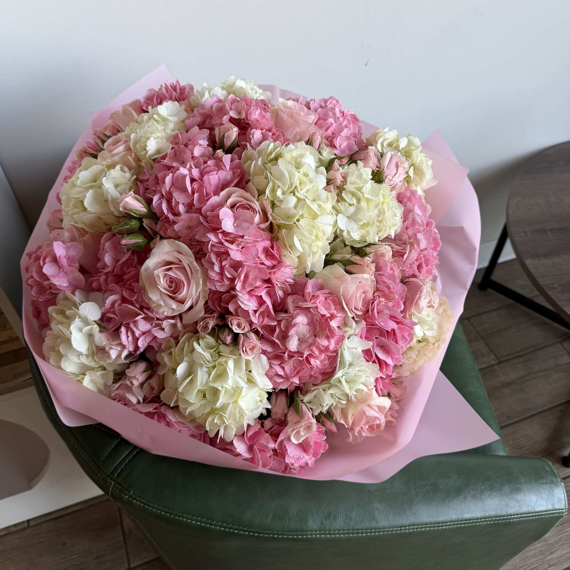 Large pink and white bouquet with roses and hydrangeas wrapped in pink paper