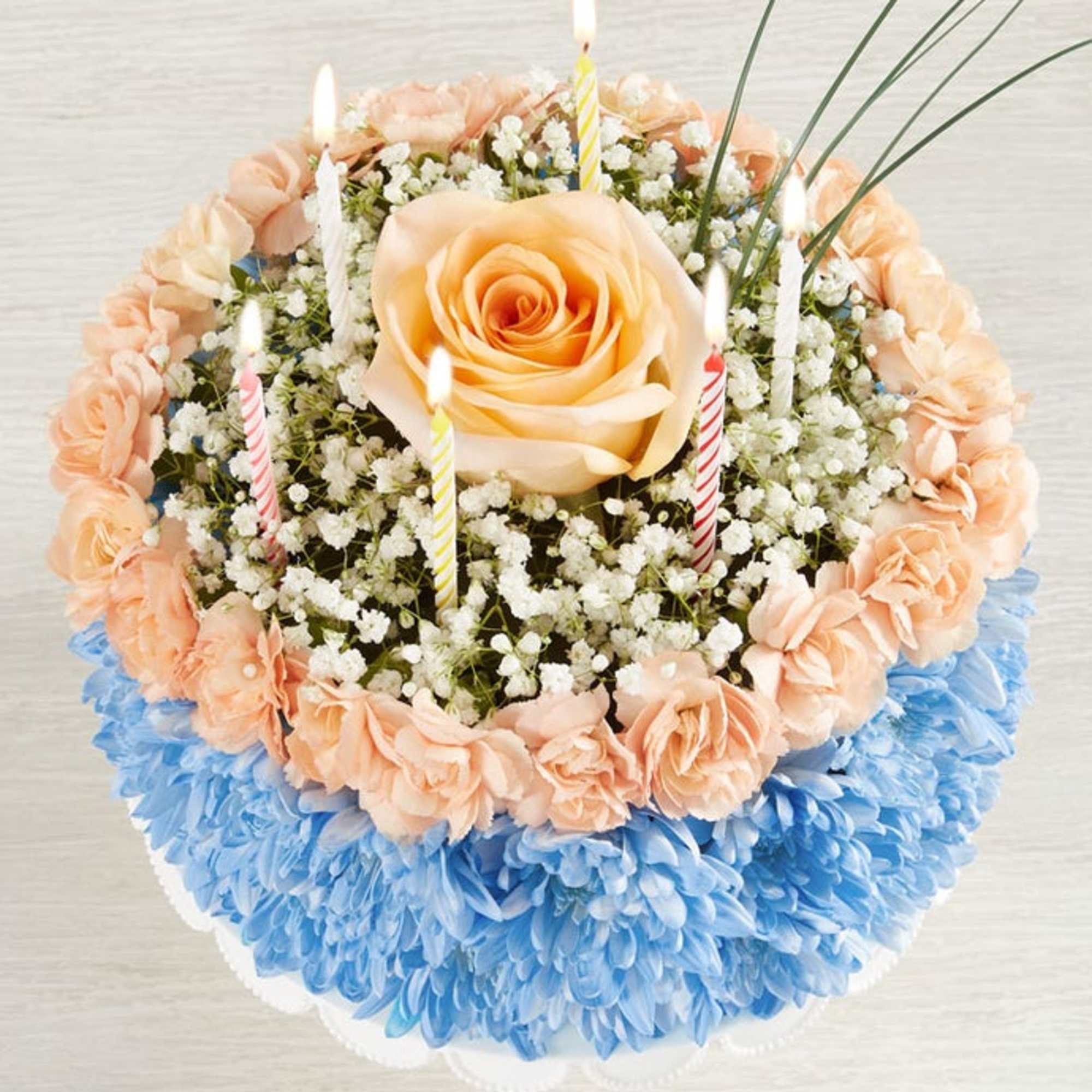 Round floral cake with candles and pastel flowers