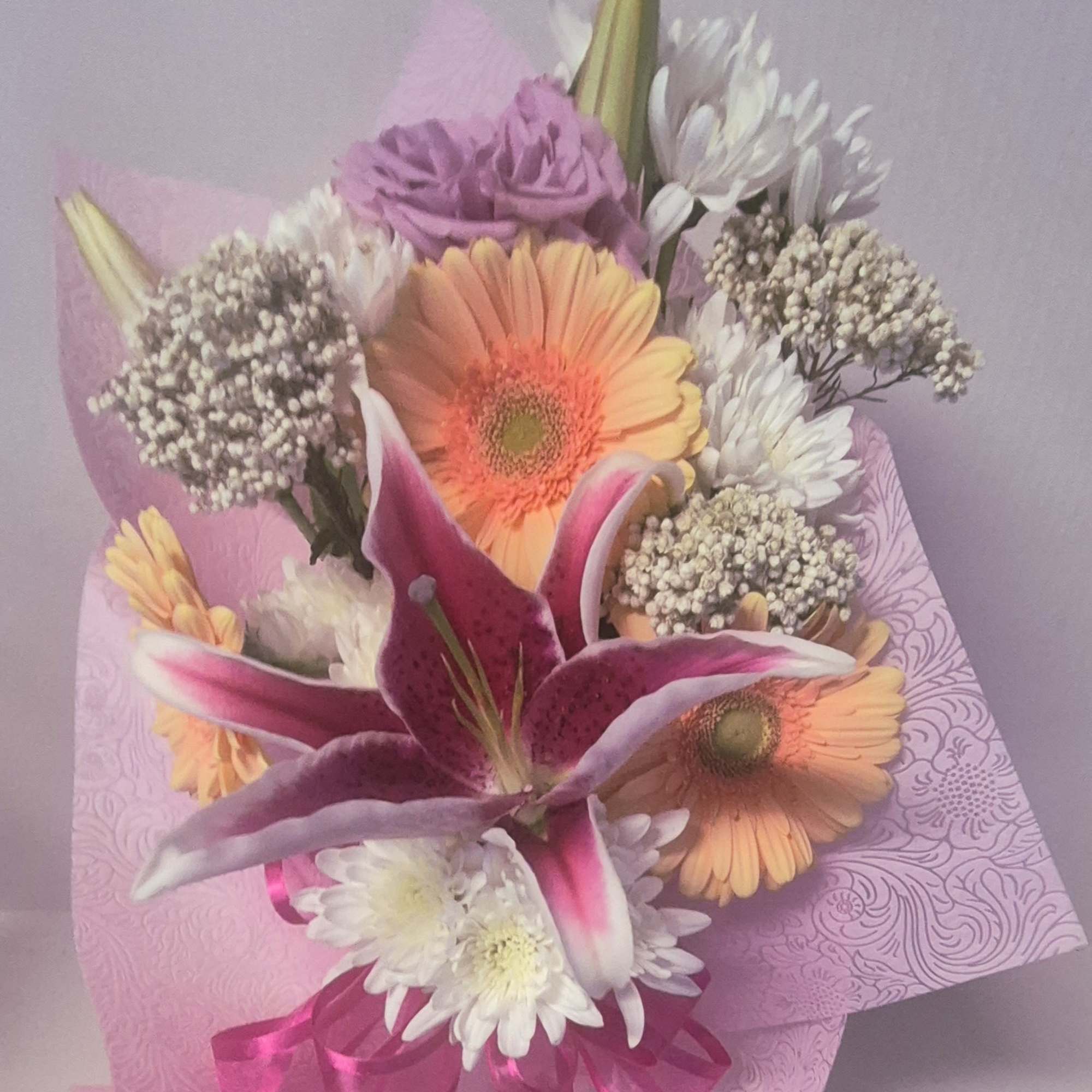 Assorted flowers which may vary, presented in a designer embossed floral wrap