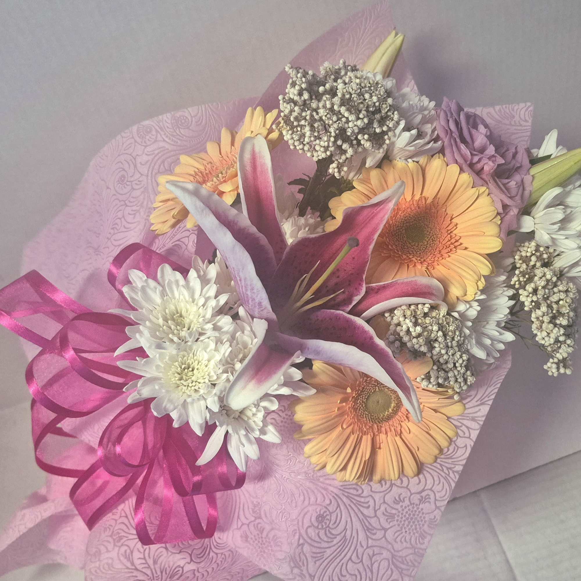 Assorted flowers which may vary, presented in a designer embossed floral wrap