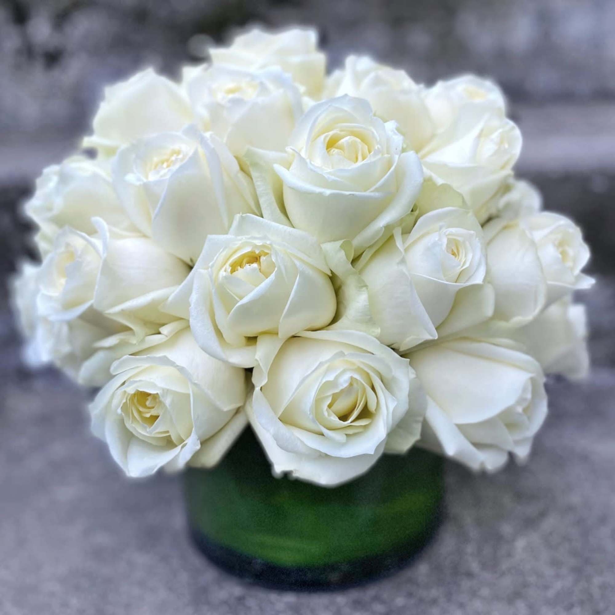 White roses arranged in a green glass vase