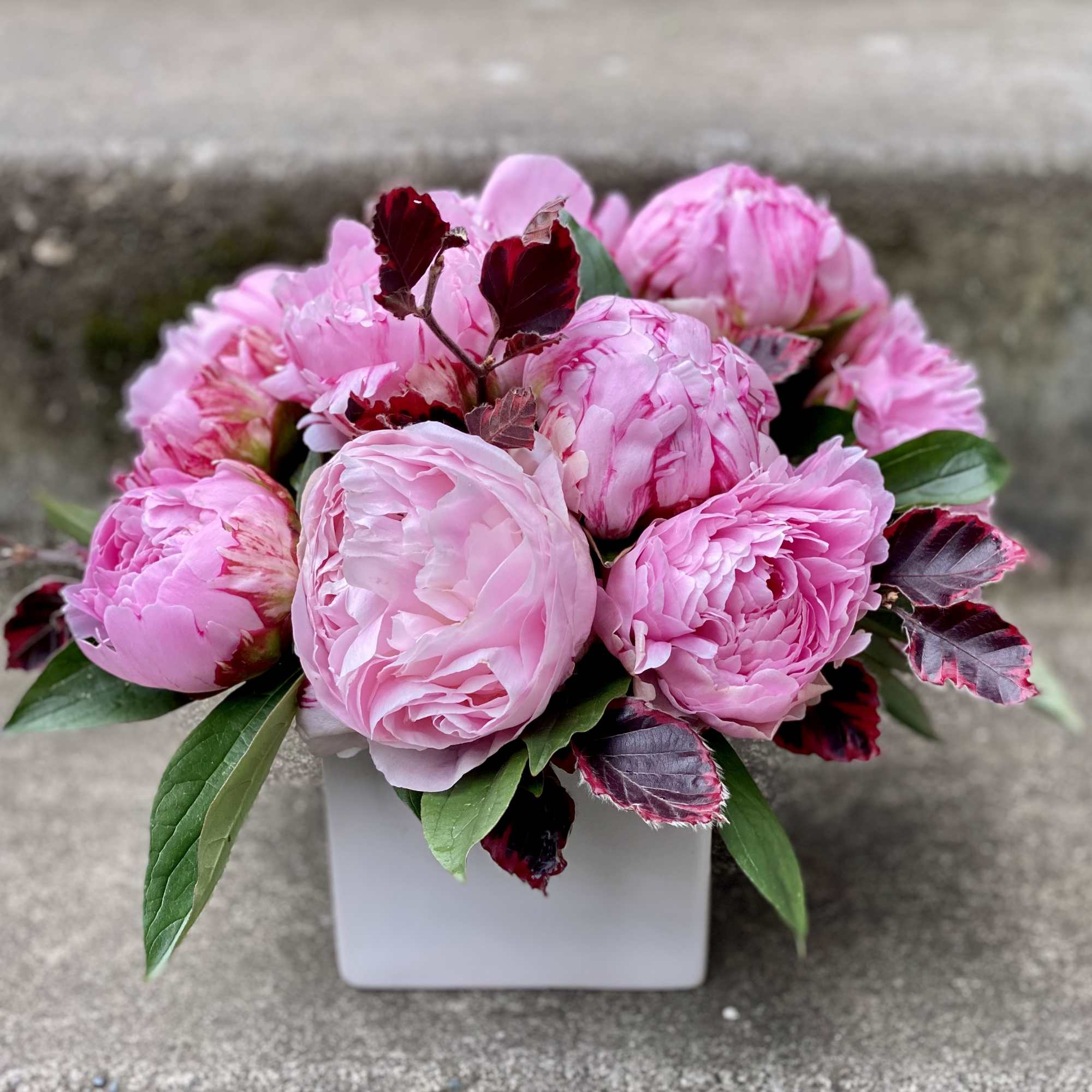 Pink peony bouquet in a white square vase