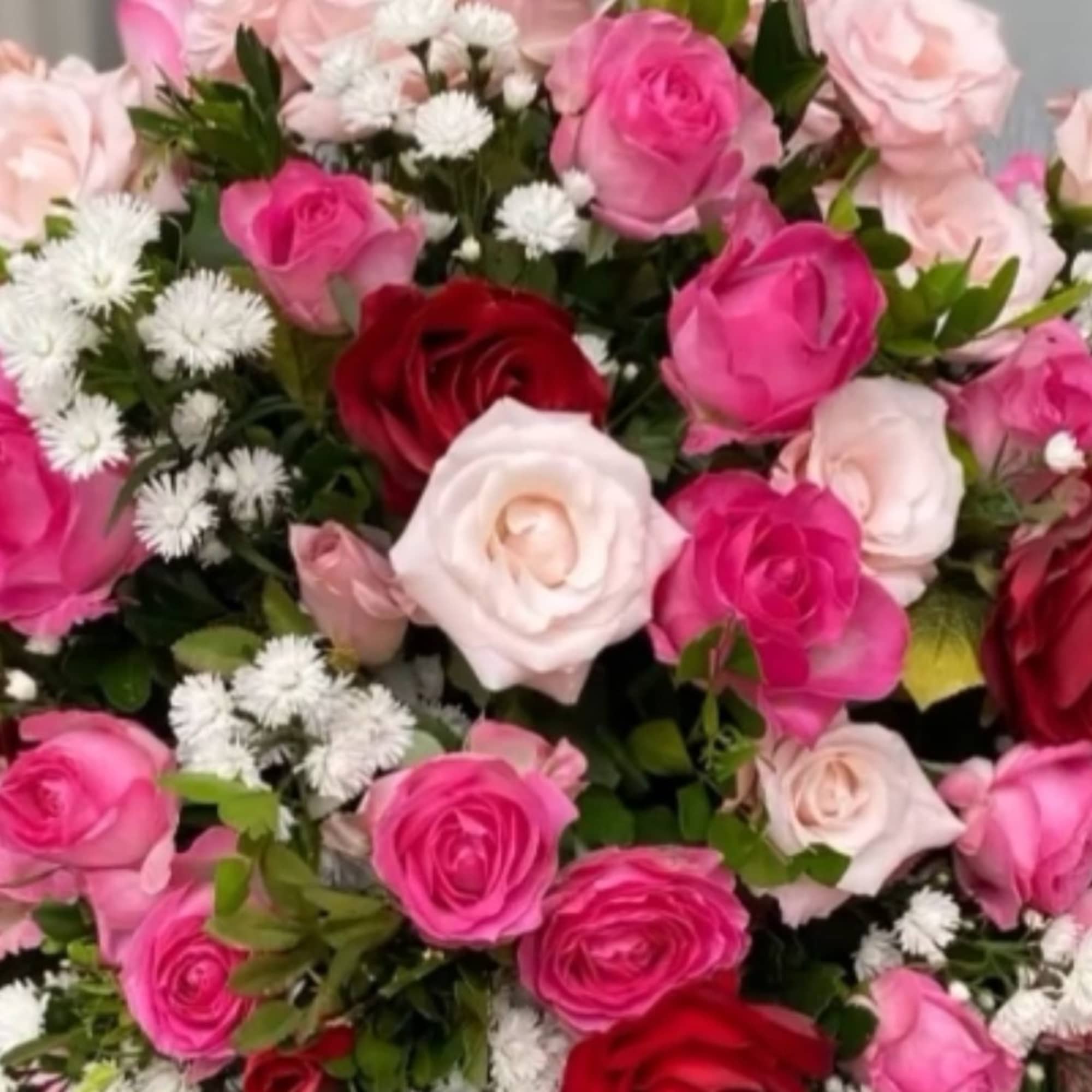 Bouquet of pink, red, and white roses with small white filler flowers