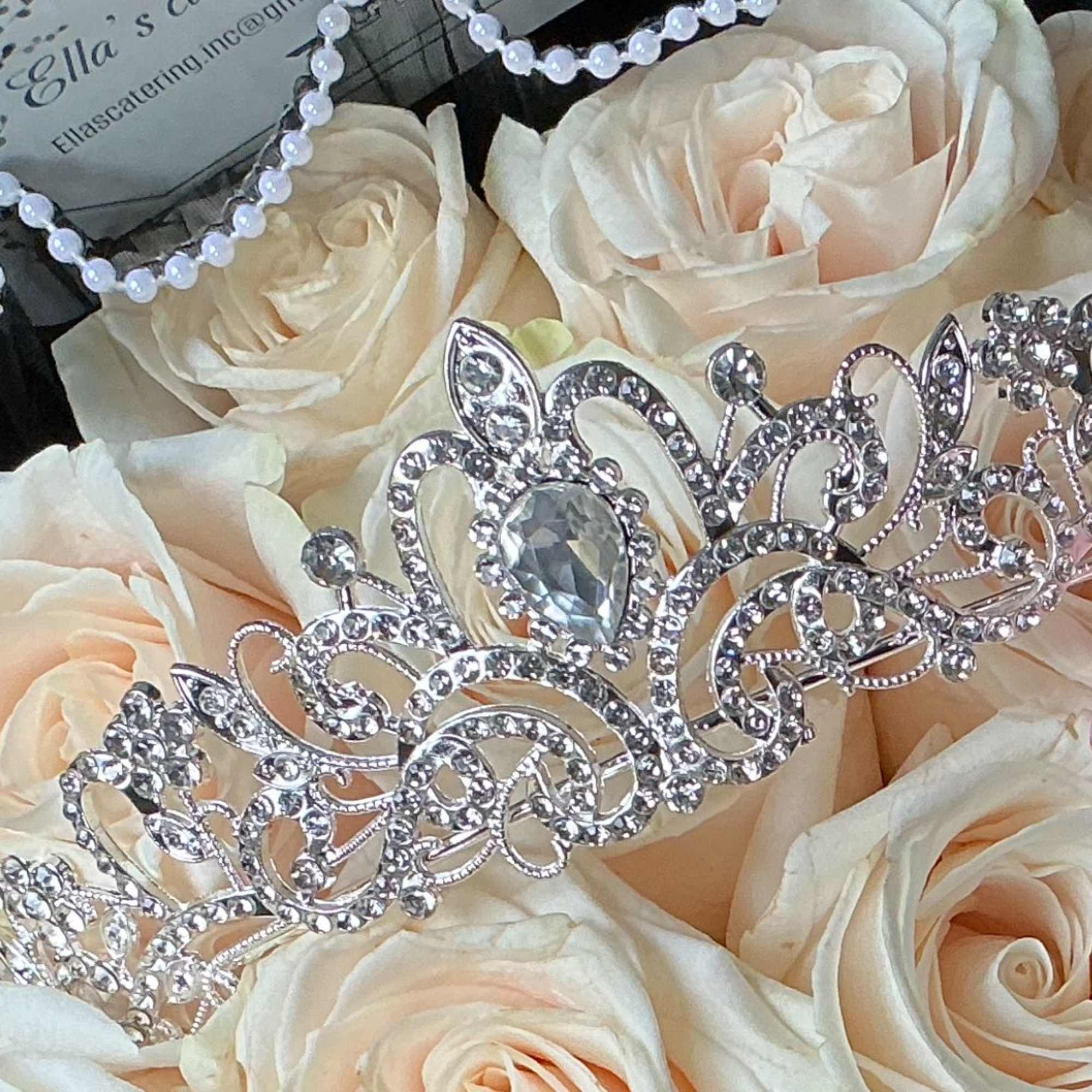 Cream roses with a jeweled tiara and pink ribbon in a black box