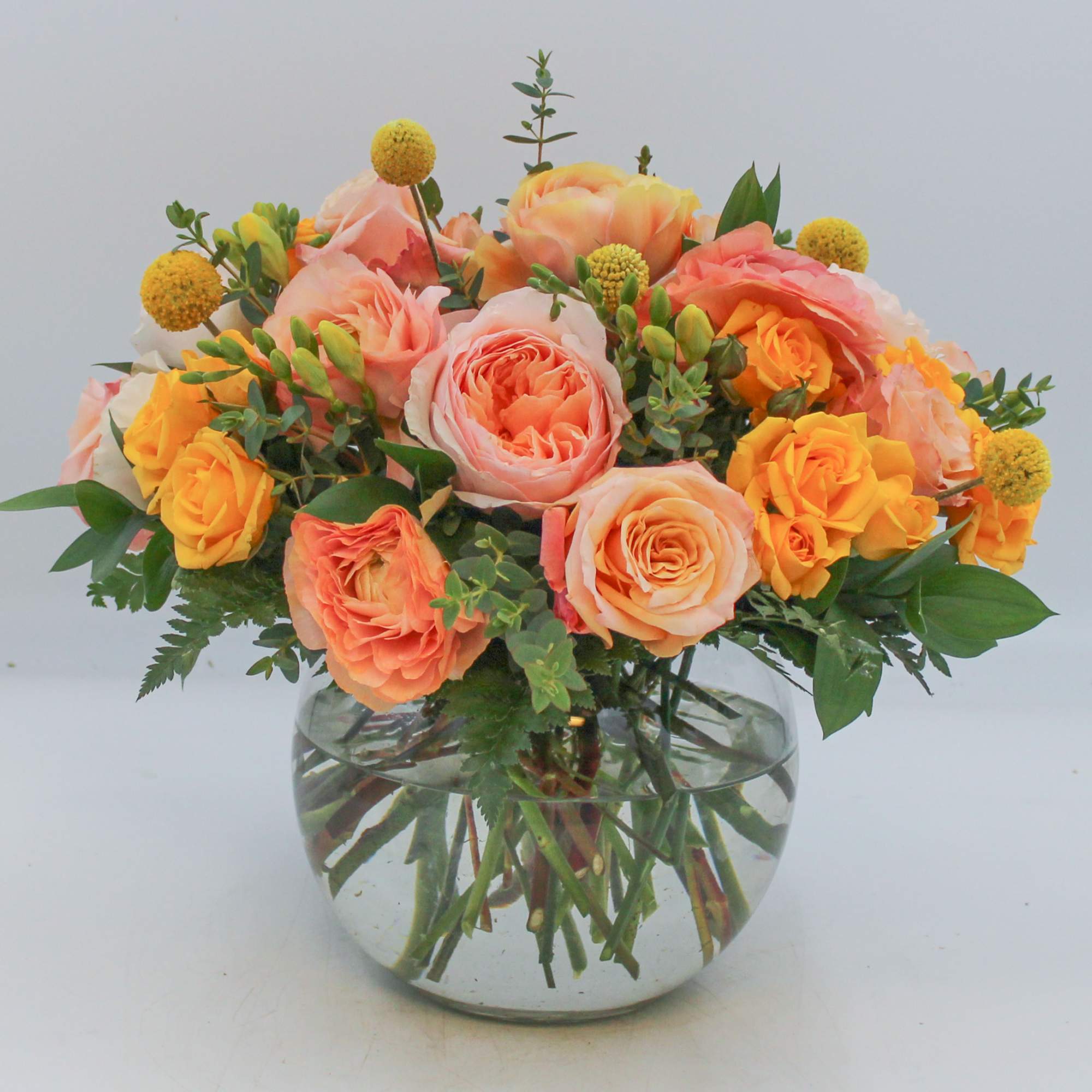 Peach and yellow roses arranged in a clear glass vase