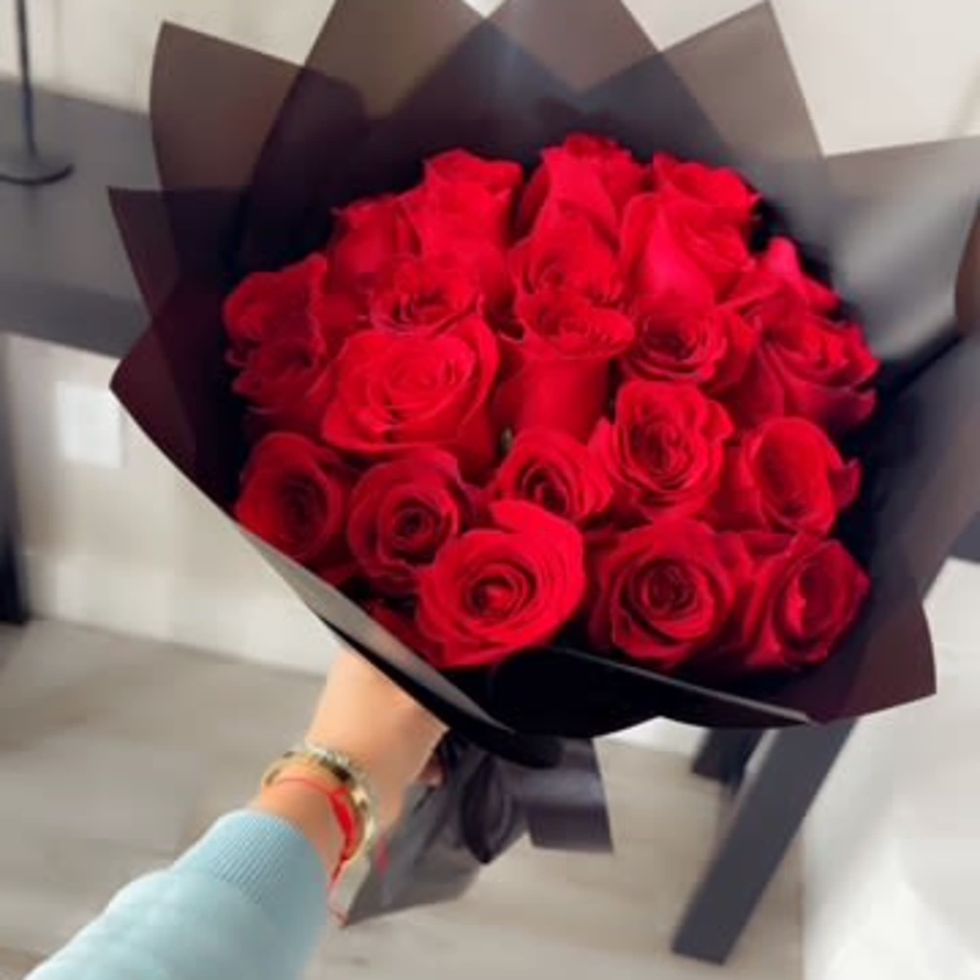 Bouquet of red roses wrapped in dark paper