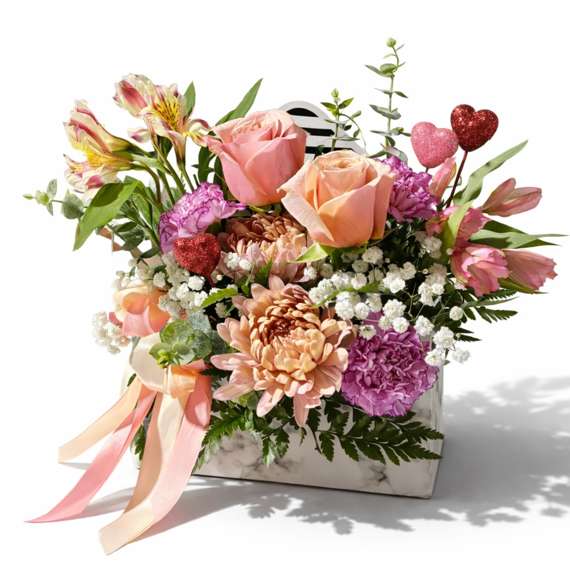 Mixed bouquet of pink and peach flowers in a marble box with heart picks