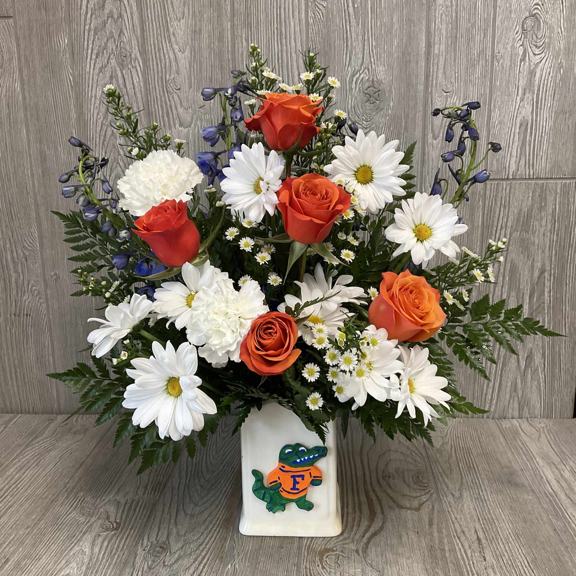 Bouquet of orange roses and white daisies in a white vase