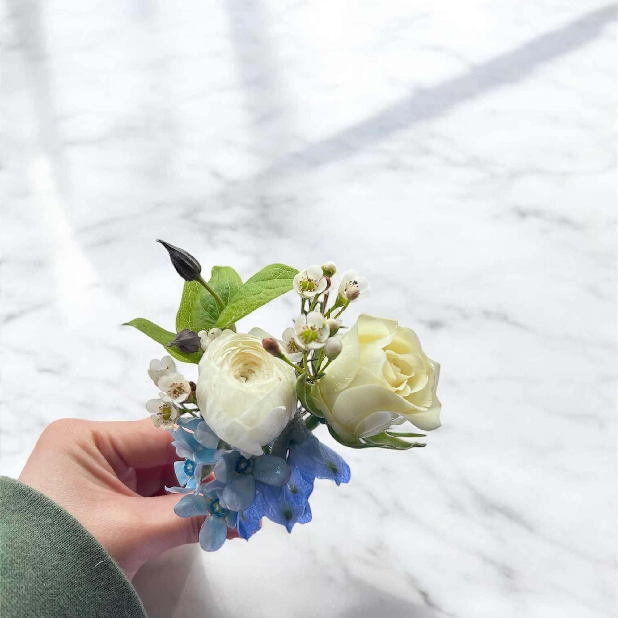 Small wedding boutonniere with white blooms and blue flowers