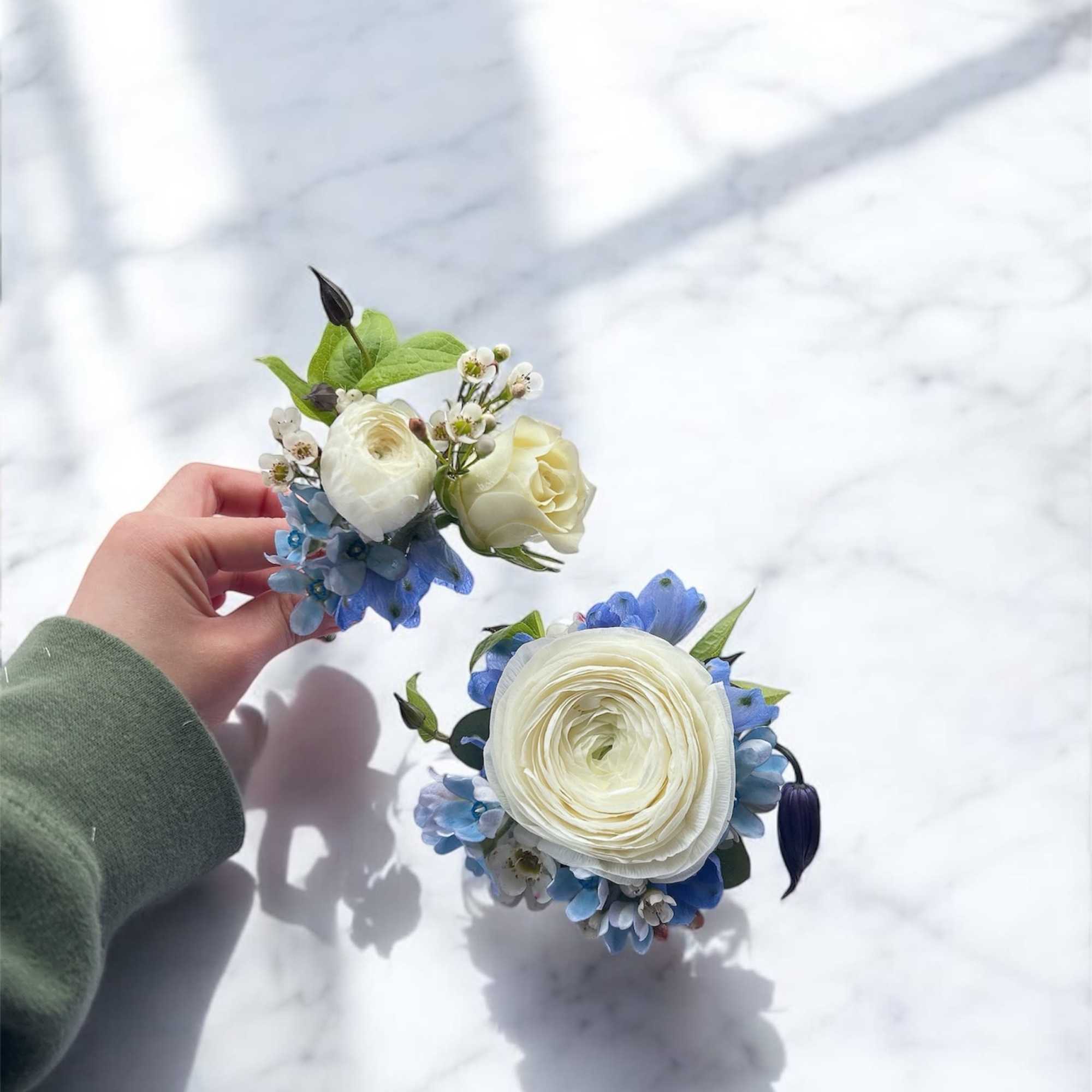 Two small floral wedding pieces with white blooms and blue accents