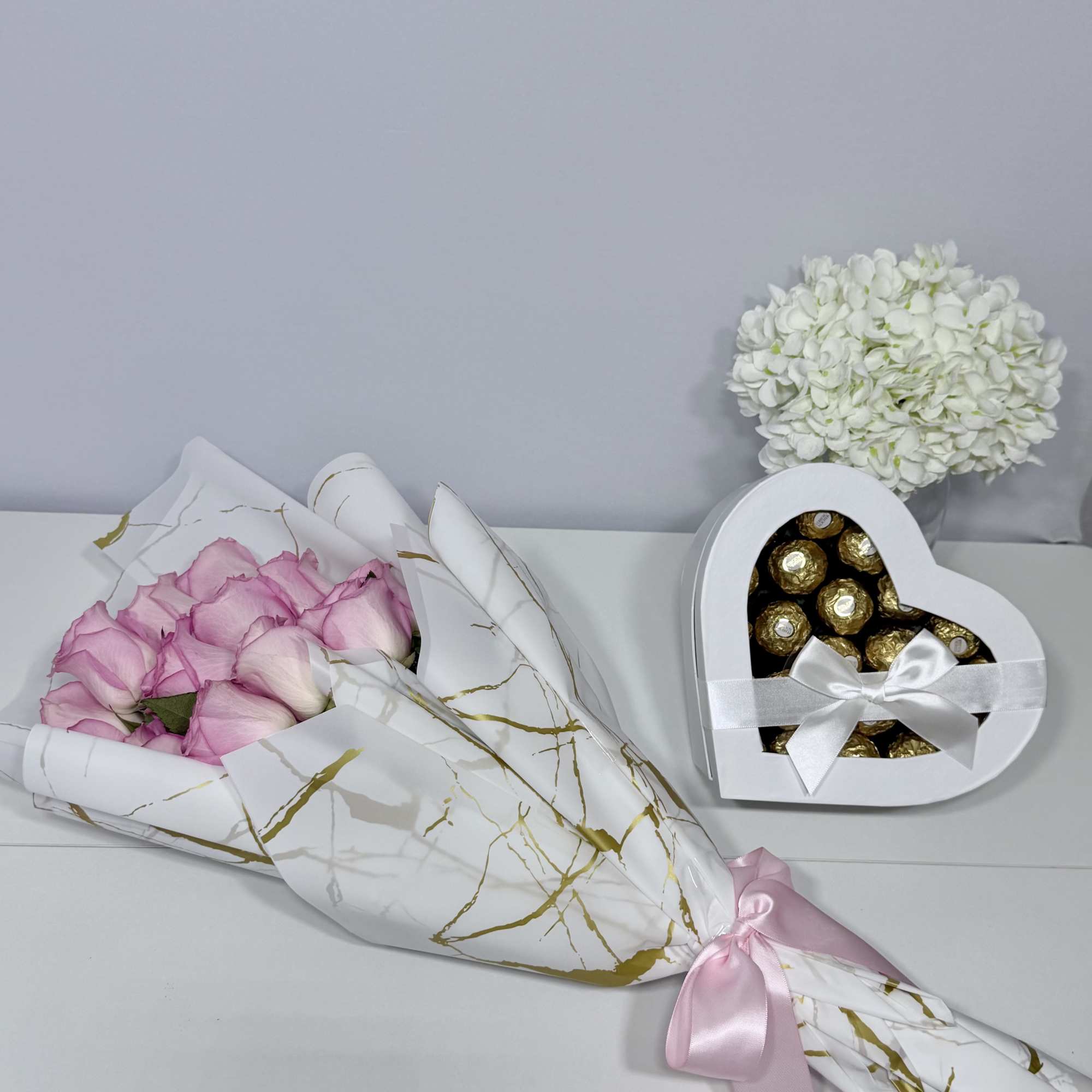 Delicate blush roses beautifully wrapped in elegant white and gold paper, paired