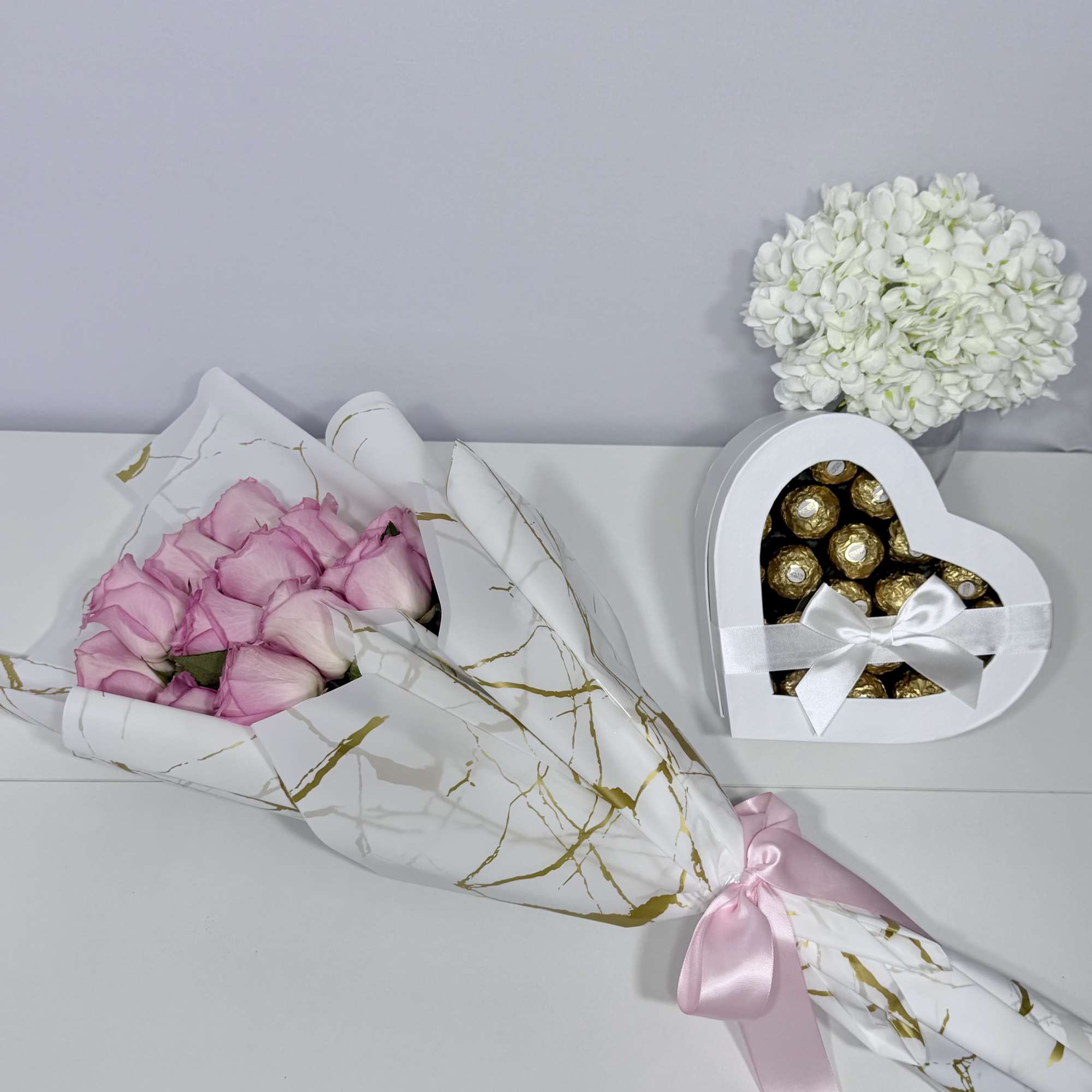 Delicate blush roses beautifully wrapped in elegant white and gold paper, paired