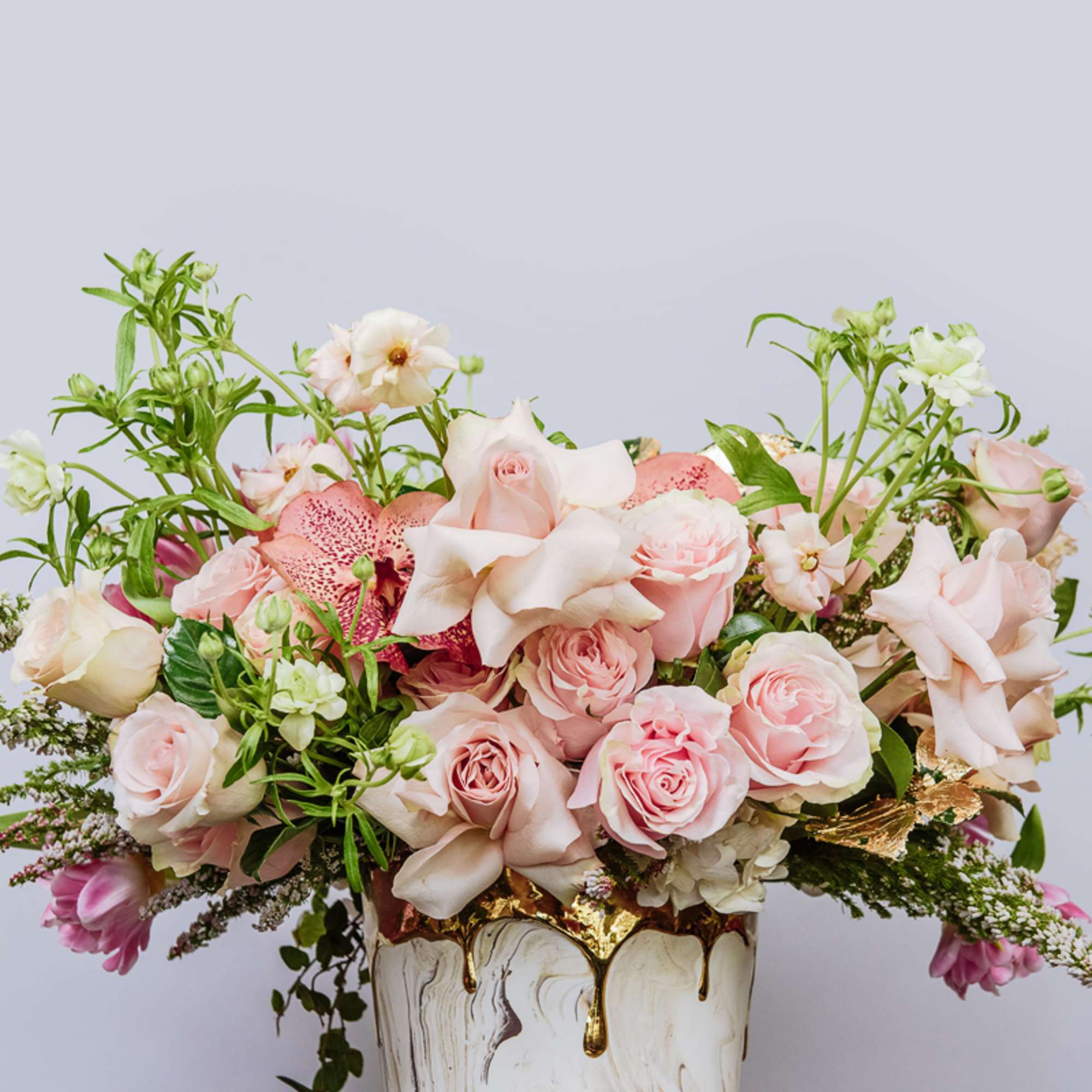 Pink and white floral arrangement in a white vase with gold accents