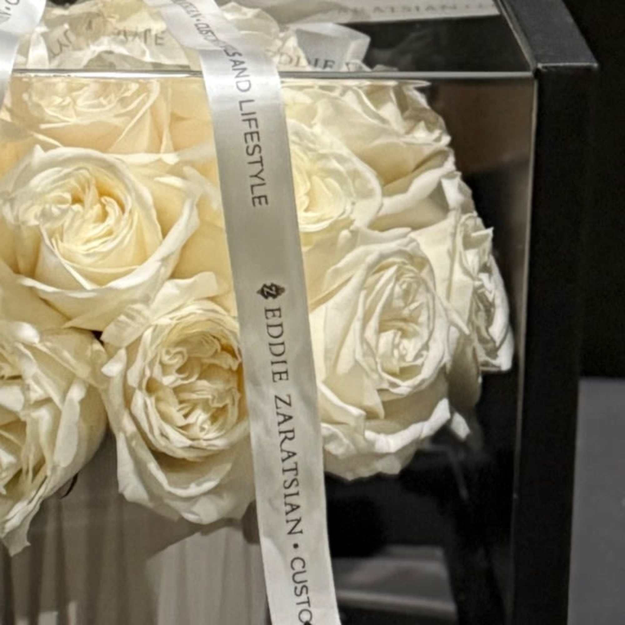 Cream roses arranged in a black gift box with a white ribbon.