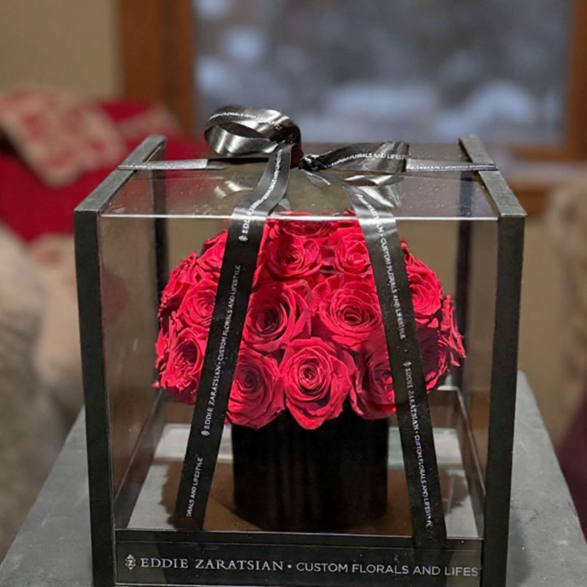Red rose arrangement in a clear gift box with a black ribbon